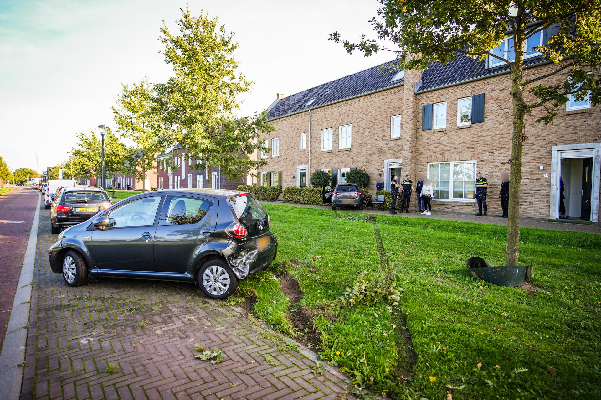 Auto belandt via busbaan, fietspad, parkeervak, grasveld, sloot, en stoep in voortuin