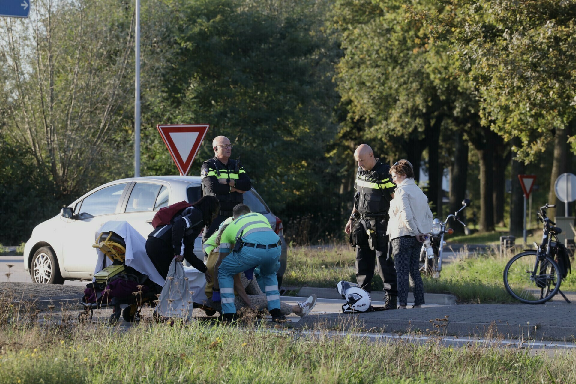 Omstanders helpen gewonde vrouw na ongeval bij rotonde in Schijndel