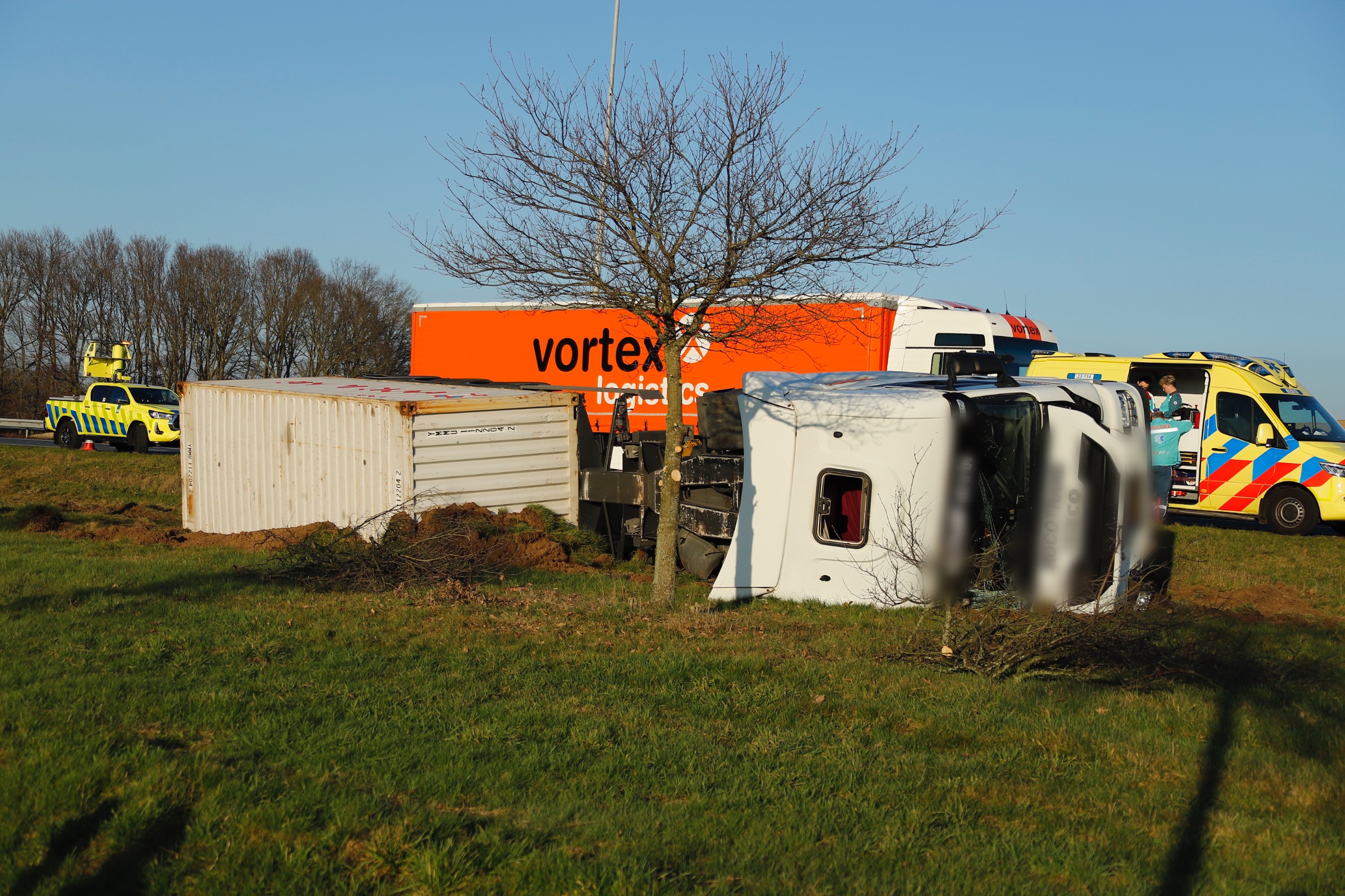 UPDATE: Vrachtwagen kiept om en belandt naast de snelweg