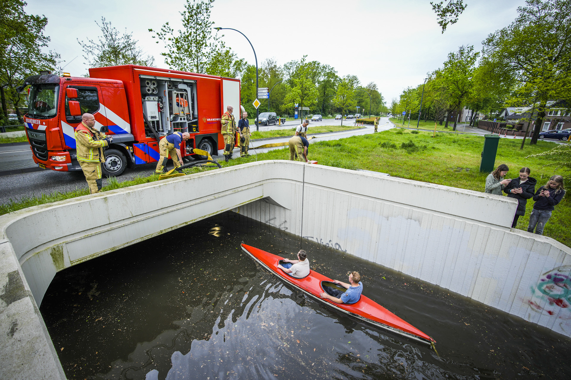 Jongeren varen met kano in ondergelopen fietstunnel