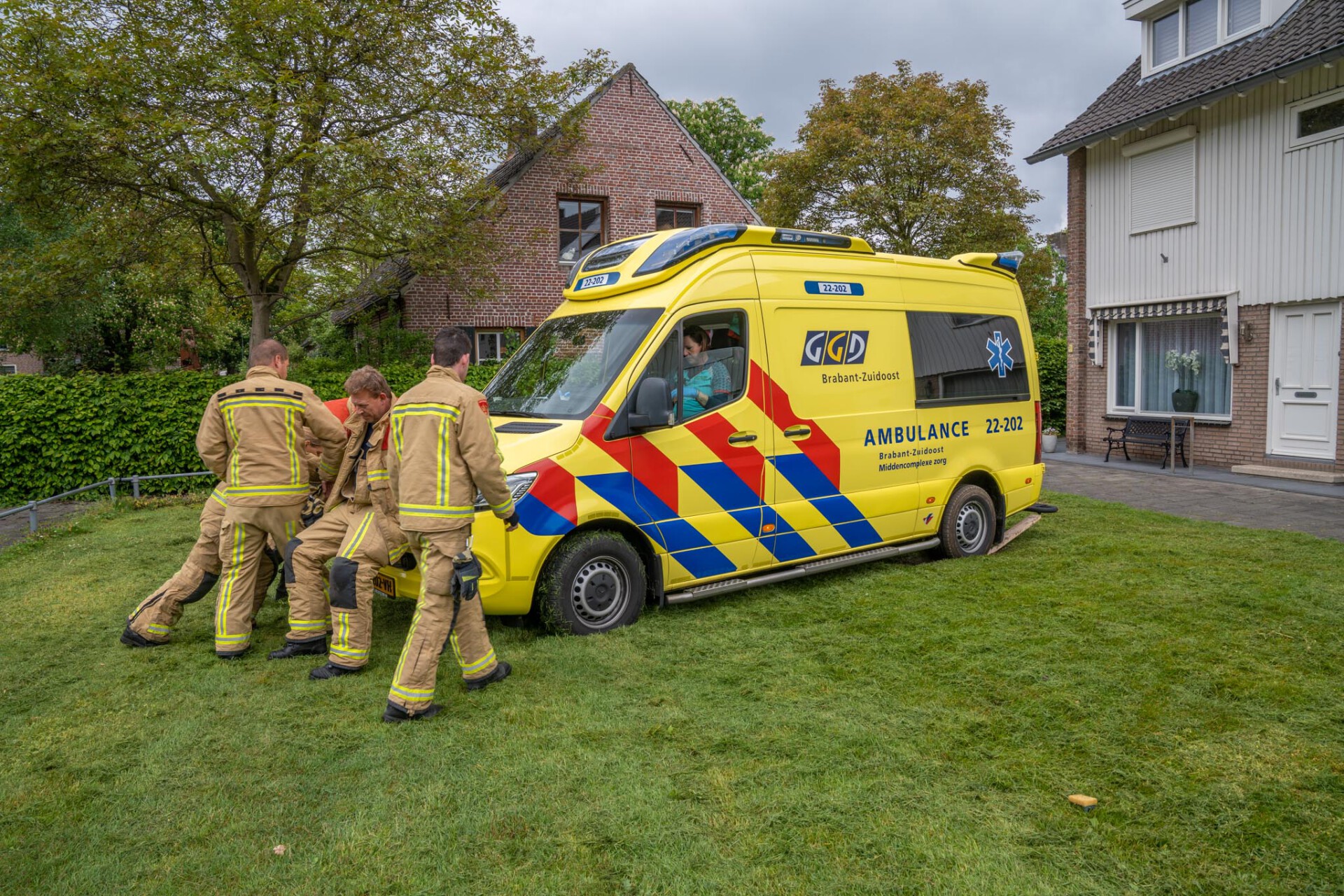 Ambulance staat vast in gras, brandweer schiet te hulp
