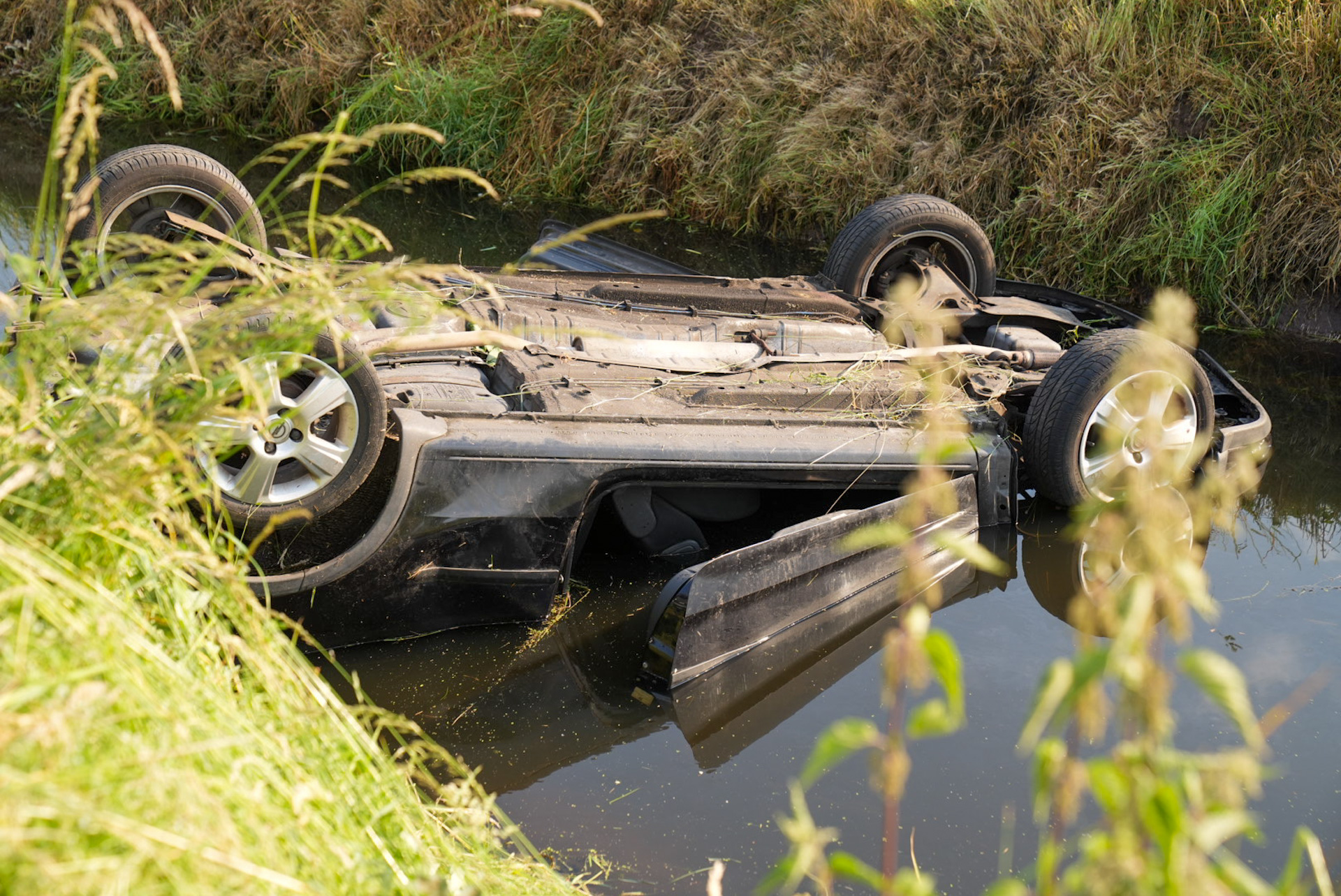 Auto komt op de kop in de sloot terecht