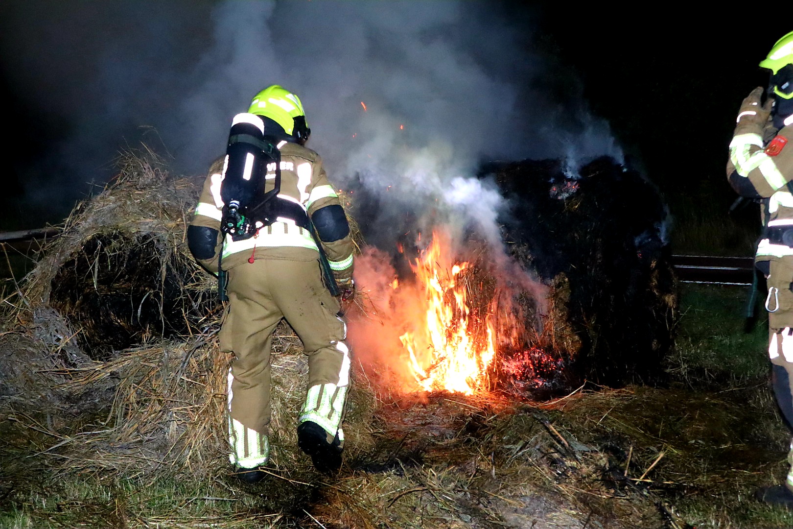 Brandweer blust brandende hooirollen