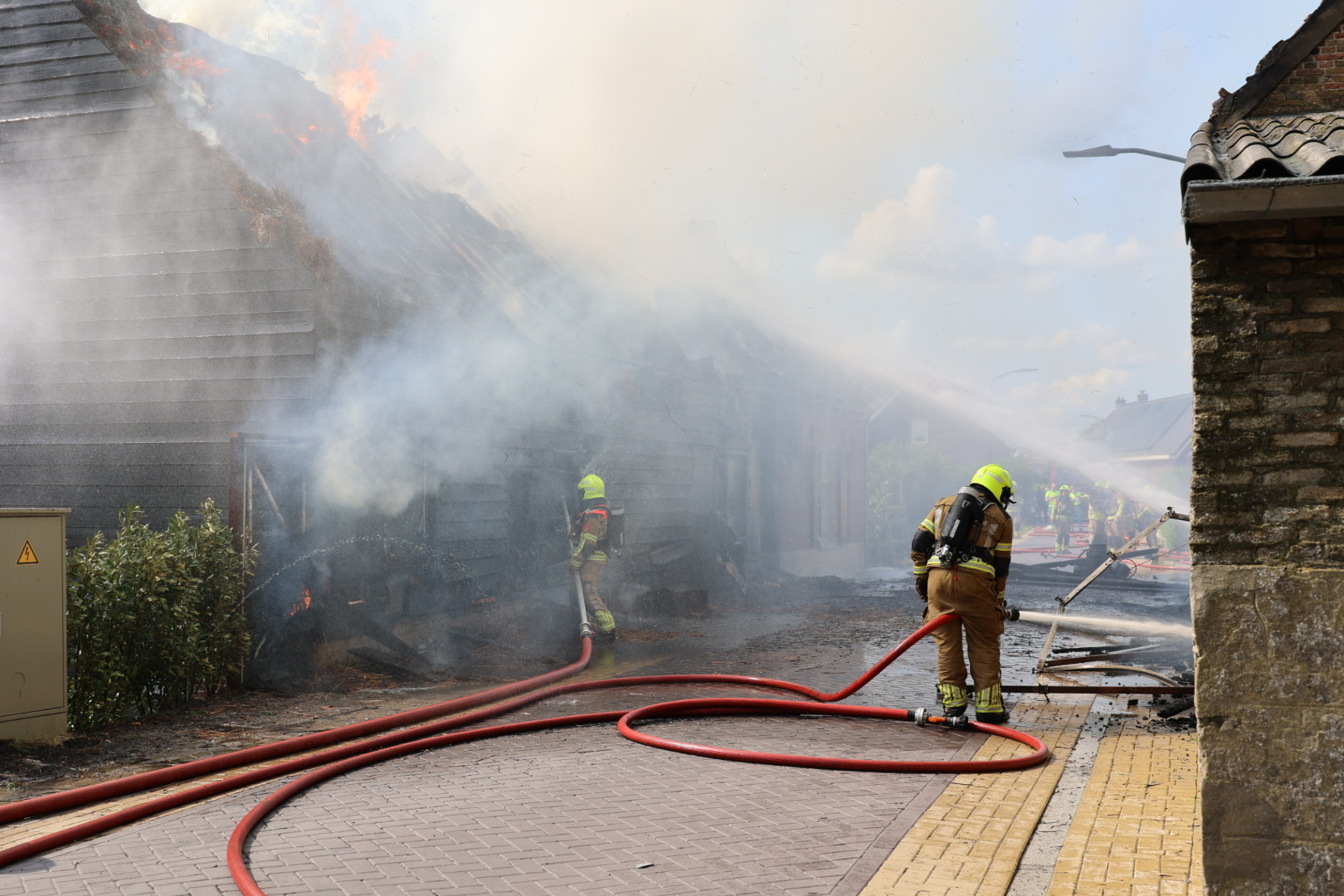 Huis met rieten dak in vlammen, vuur overgeslagen naar zorgboerderij