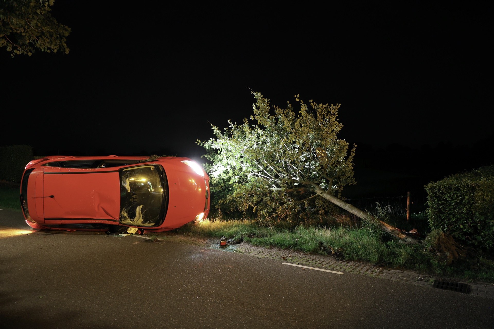 Automobilist botst tegen boom en belandt met voertuig op zijn kant