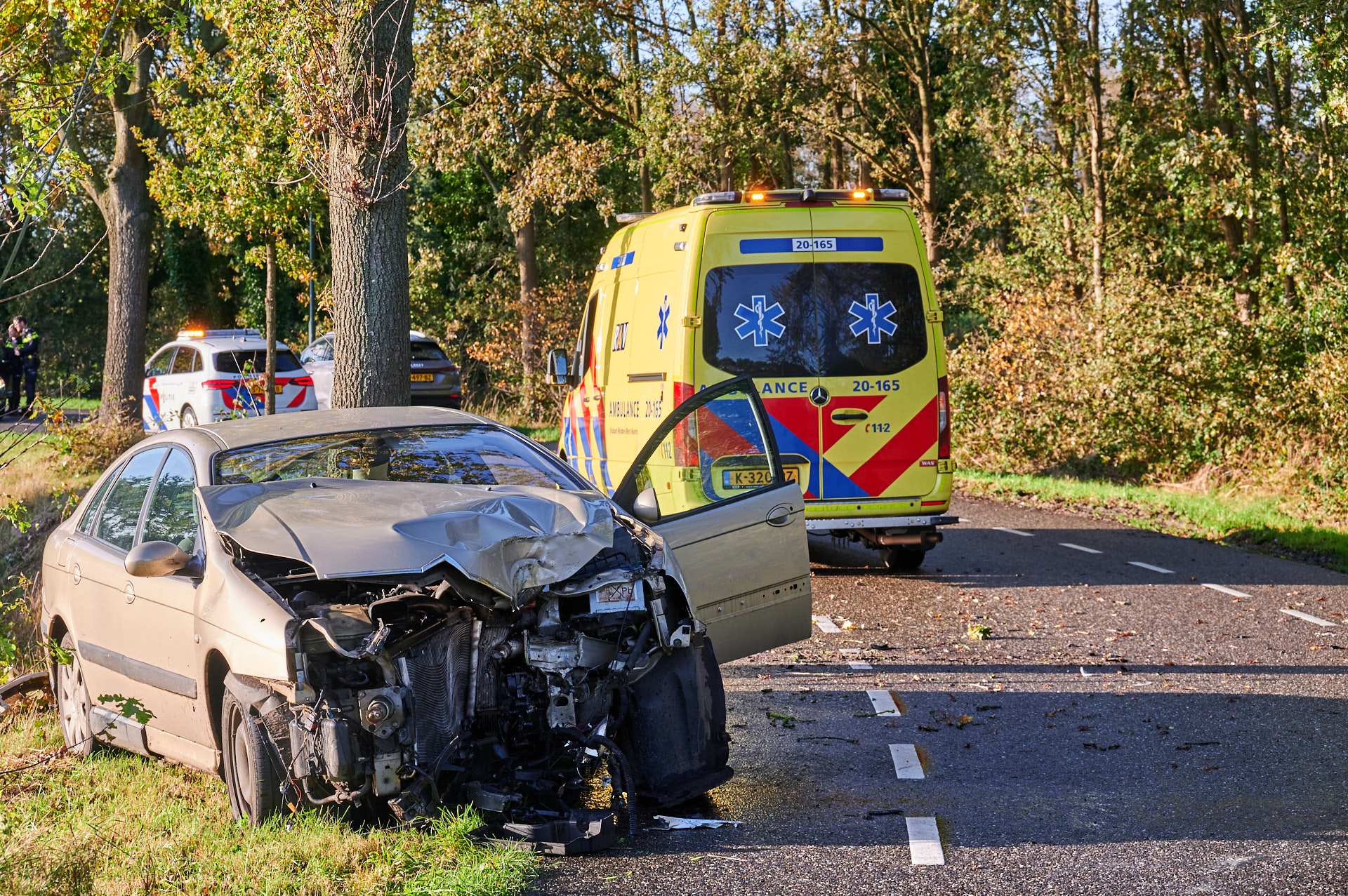 Auto klapt tegen boom, bijna volledige voorkant breekt los