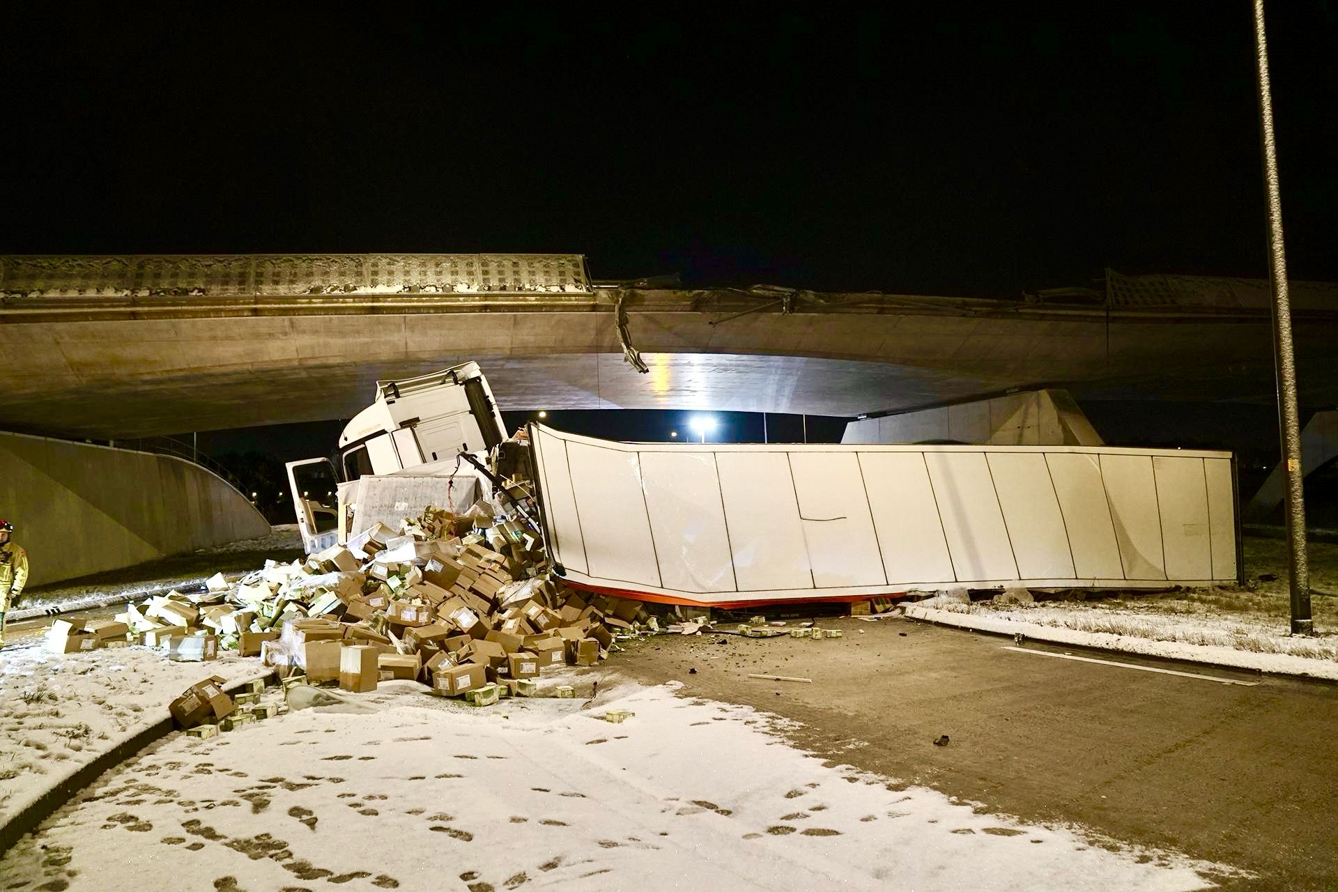 Vrachtwagen vol doperwten stort van viaduct