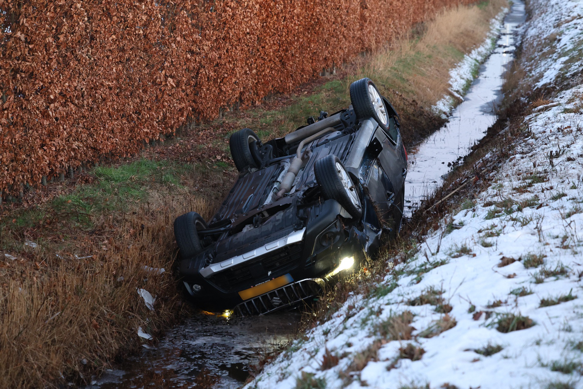 Auto belandt ondersteboven in sloot na inhaalpoging van bus