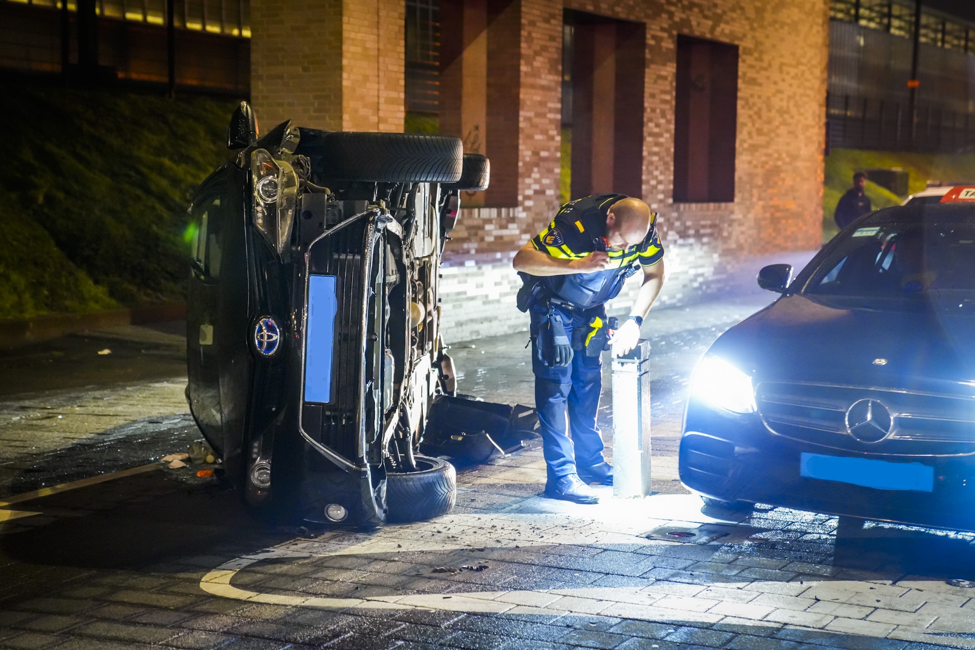 Taxi raakt paaltje en belandt op z’n kant