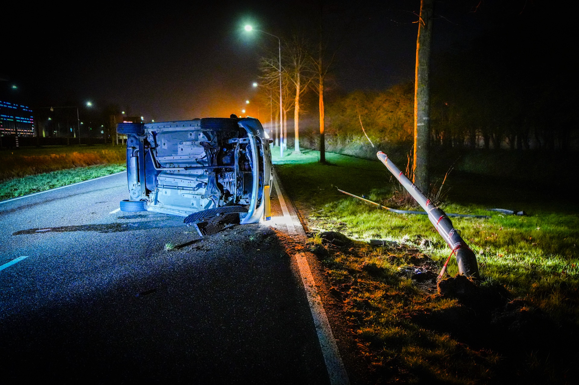 Auto op z’n kant na botsing tegen lantaarnpaal, bestuurder met politie mee