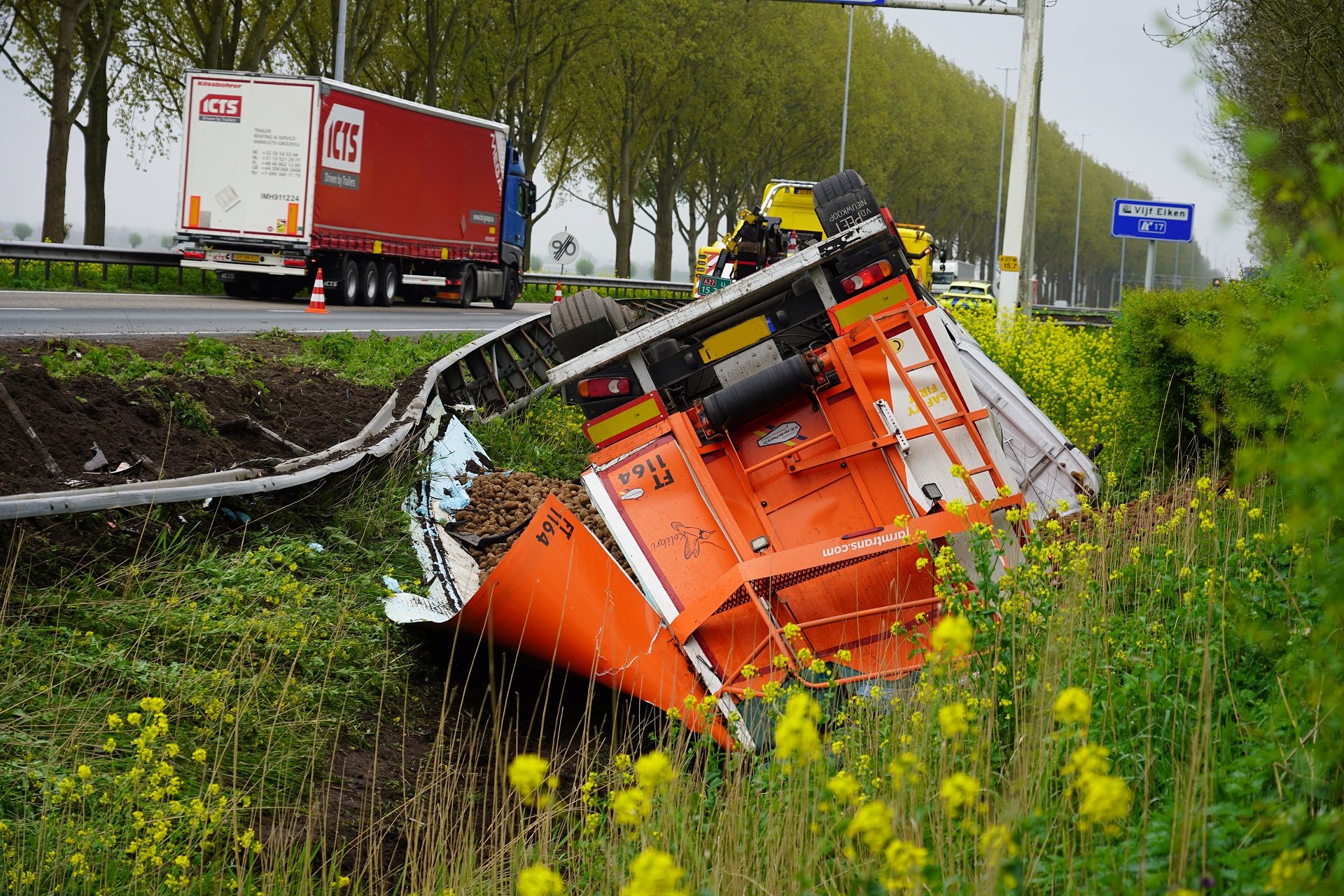 Vrachtwagen met aardappelen gekanteld langs snelweg