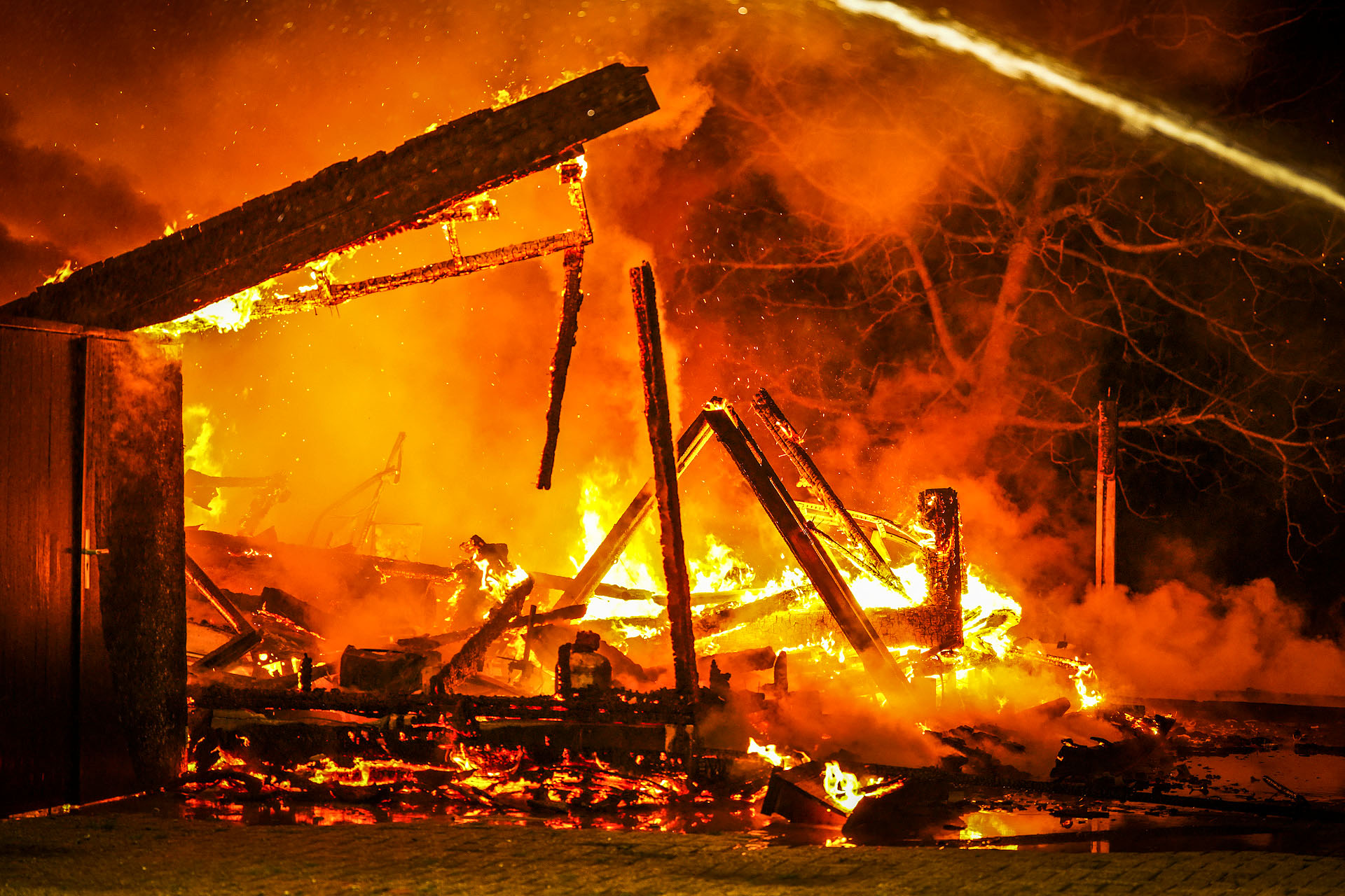 Grote uitslaande brand in opslagloods bij garagebedrijf