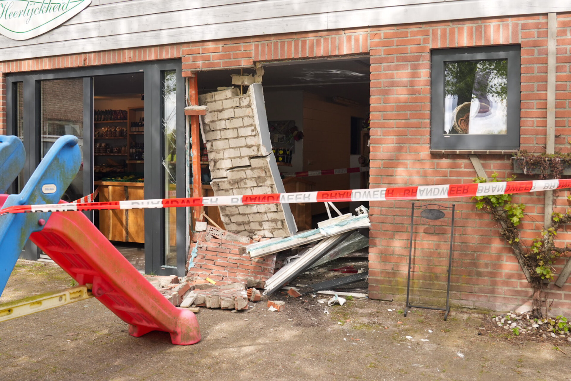 Oudere vrouw rijdt met auto door winkelpui