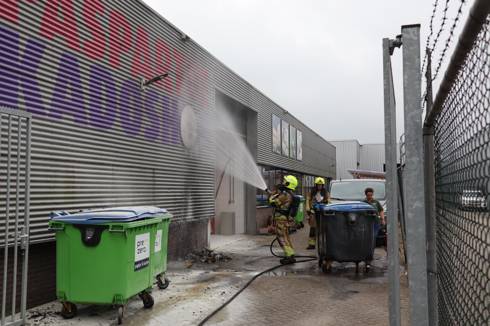 Container vliegt in brand tegen bedrijfspand