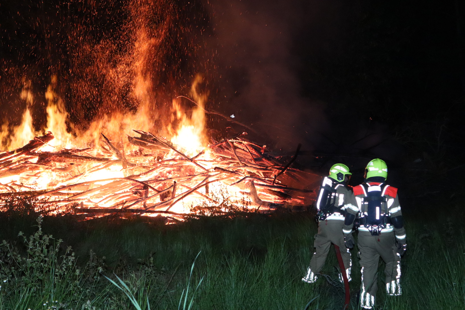 Metershoge vlammen in bos door brandende stapel takken