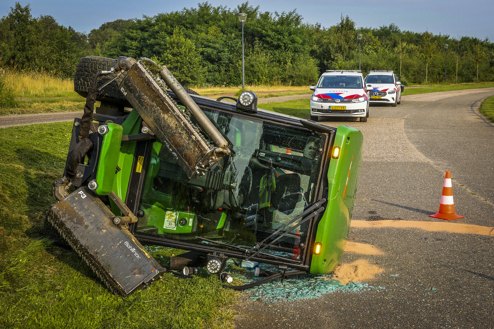Maaimachine kantelt op helling, bestuurder raakt gewond aan hand
