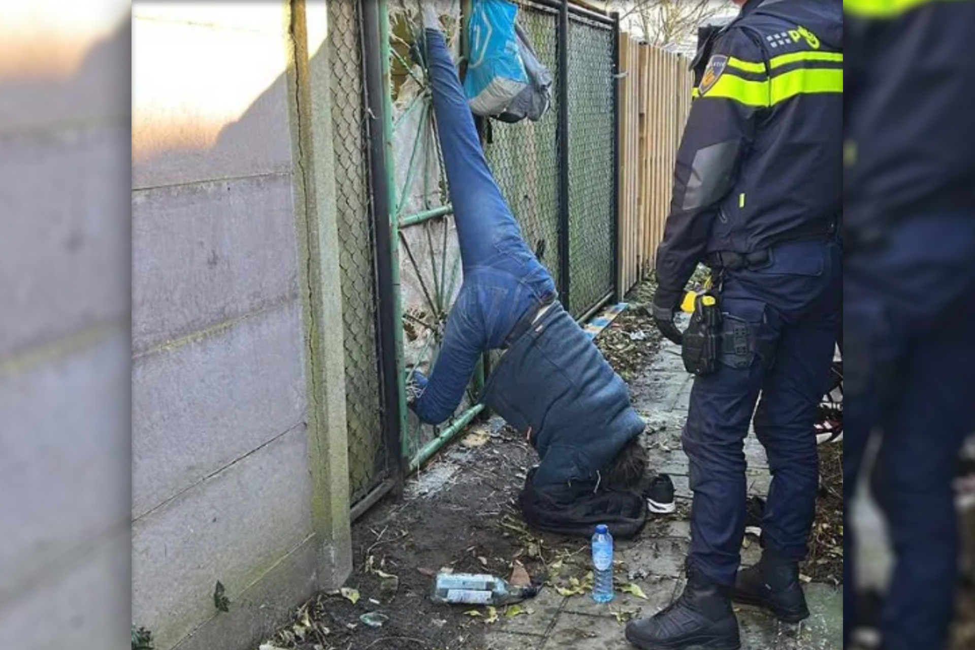 Man hangt op zijn kop vast in hek