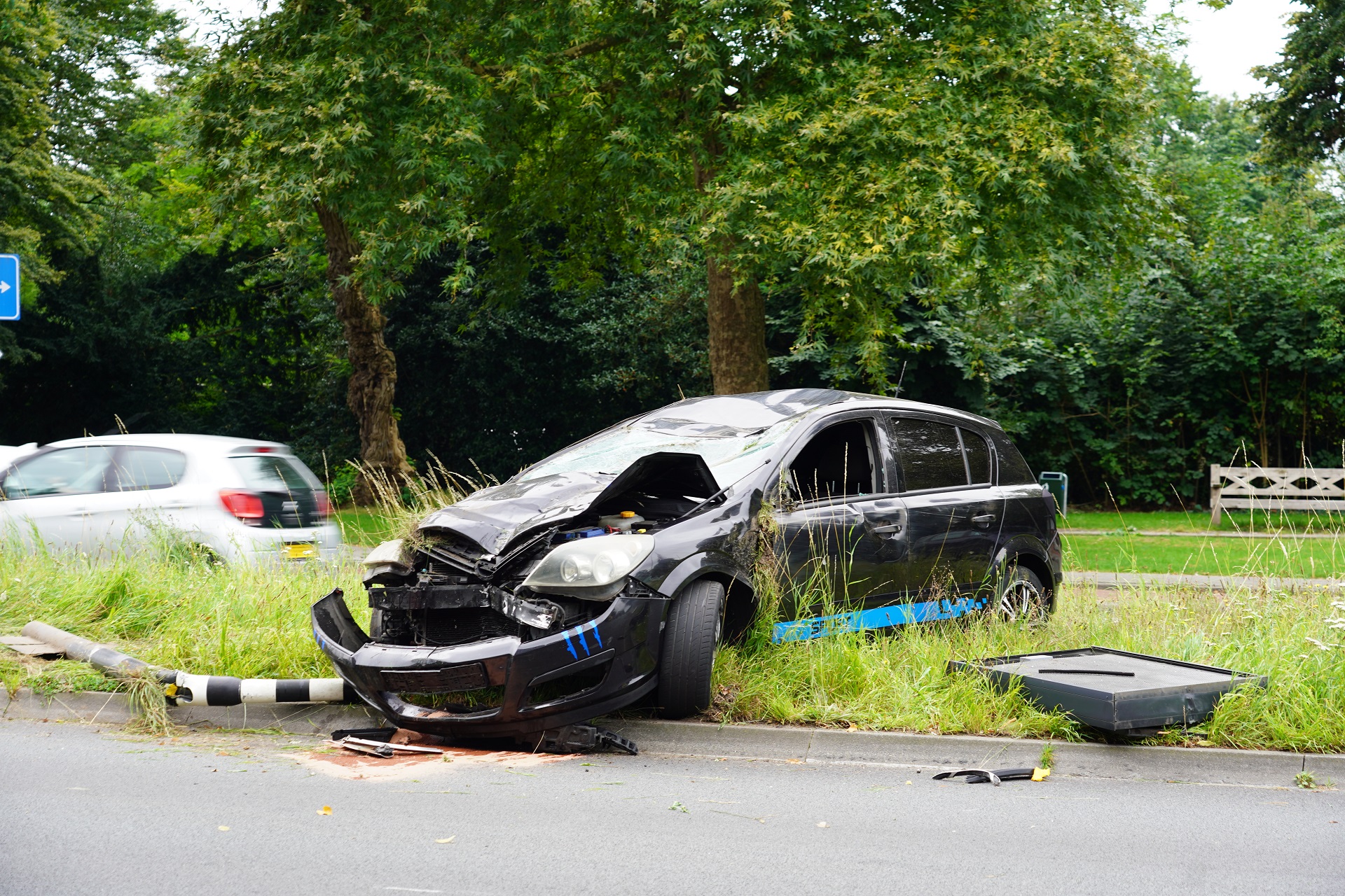 Auto ramt lantaarnpaal en stoplicht en slaat over de kop