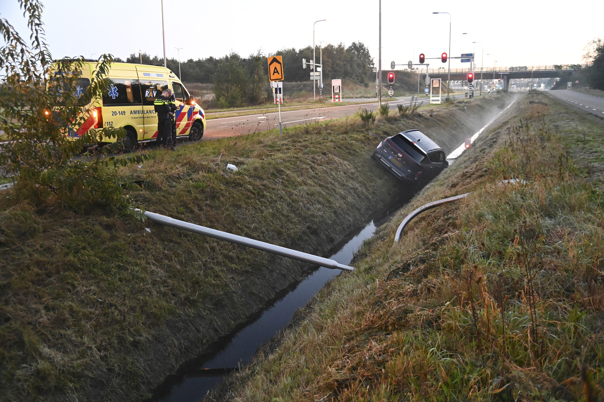 Auto ramt lantaarnpaal en belandt in sloot, bestuurder lichtgewond
