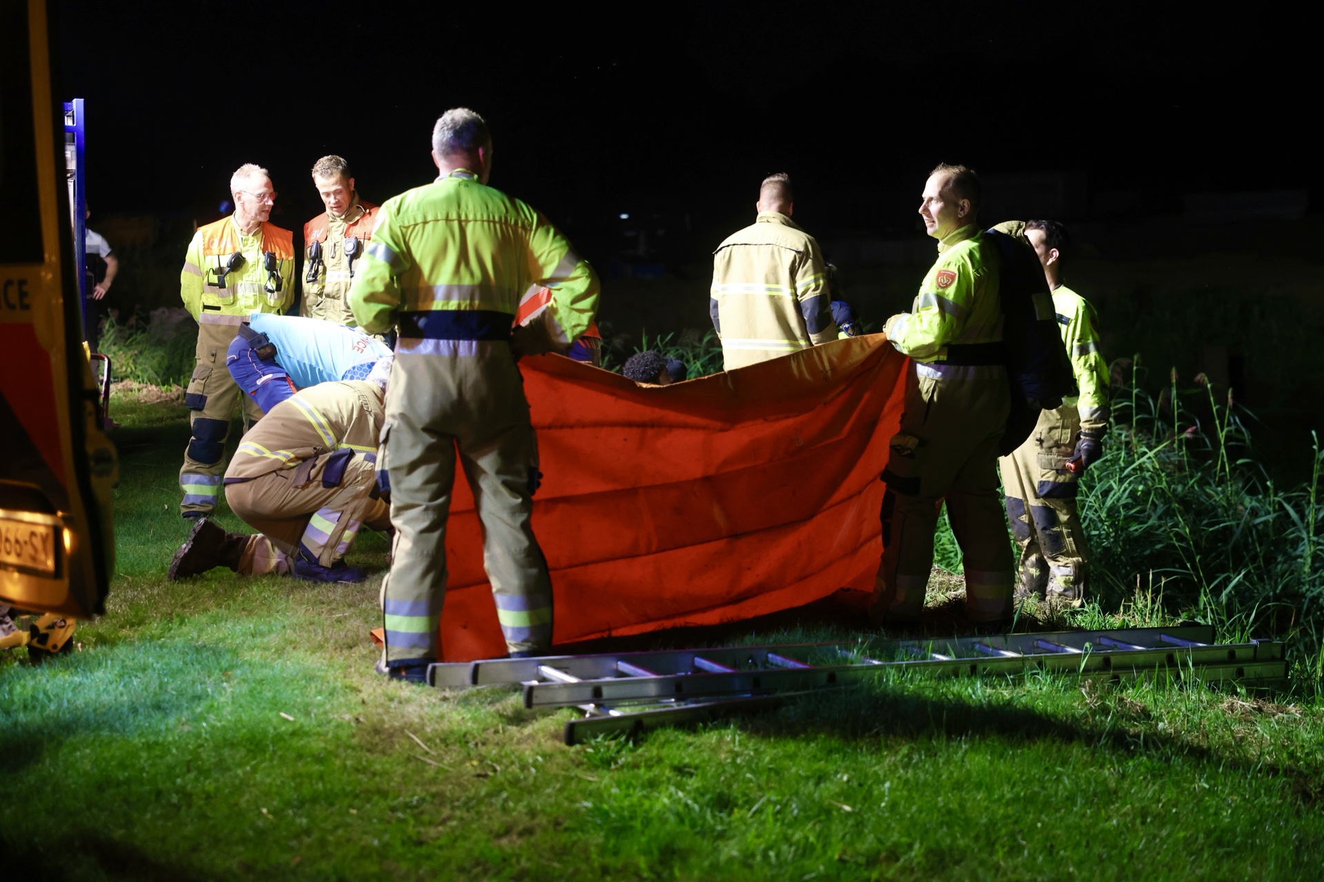 Man vast in drijfzand, omstanders schieten te hulp