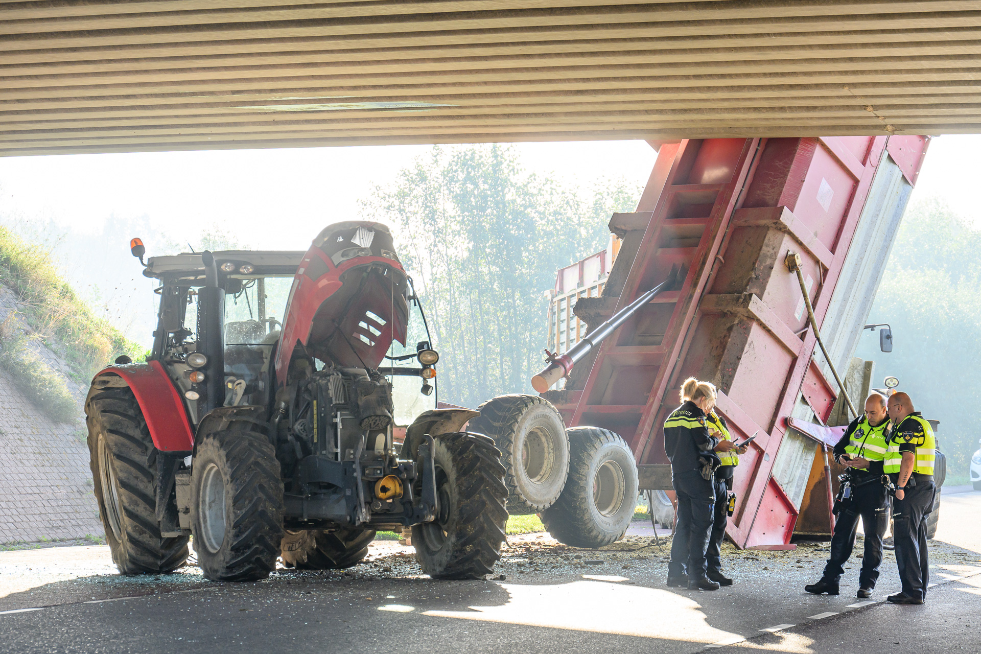Kiepkar achter tractor ramt viaduct, man gewond