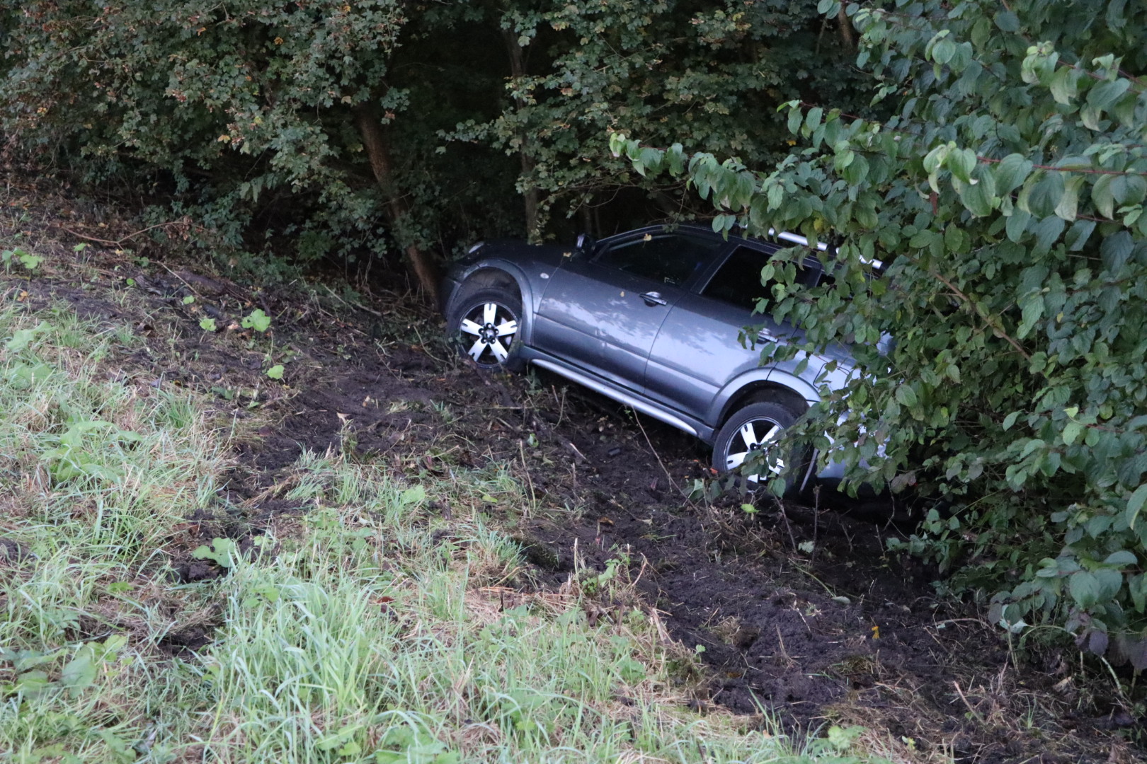 Auto raakt van de weg en belandt onder aan talud