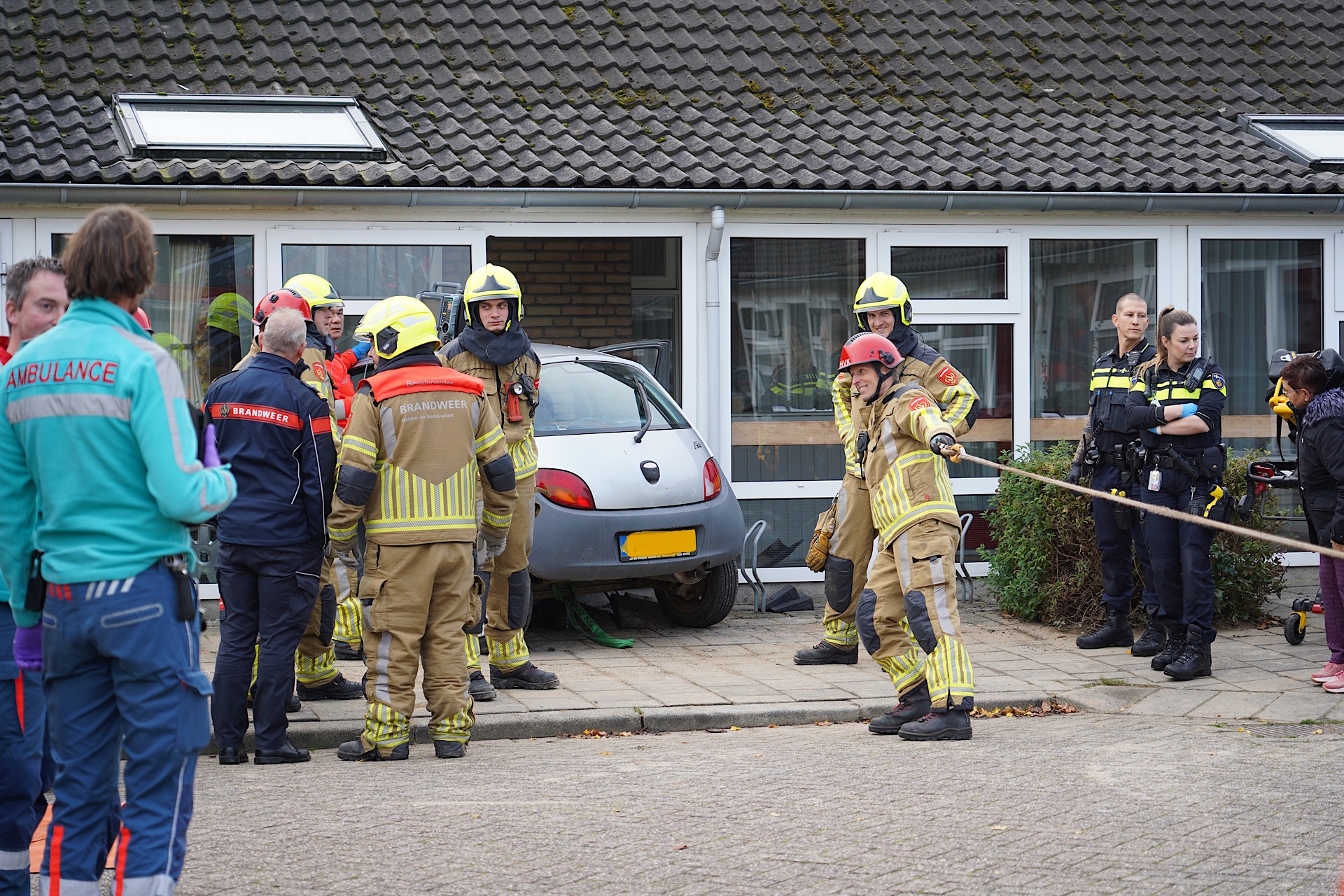 Oudere vrouw rijdt met auto gebouw binnen, brandweer bevrijdt inzittenden
