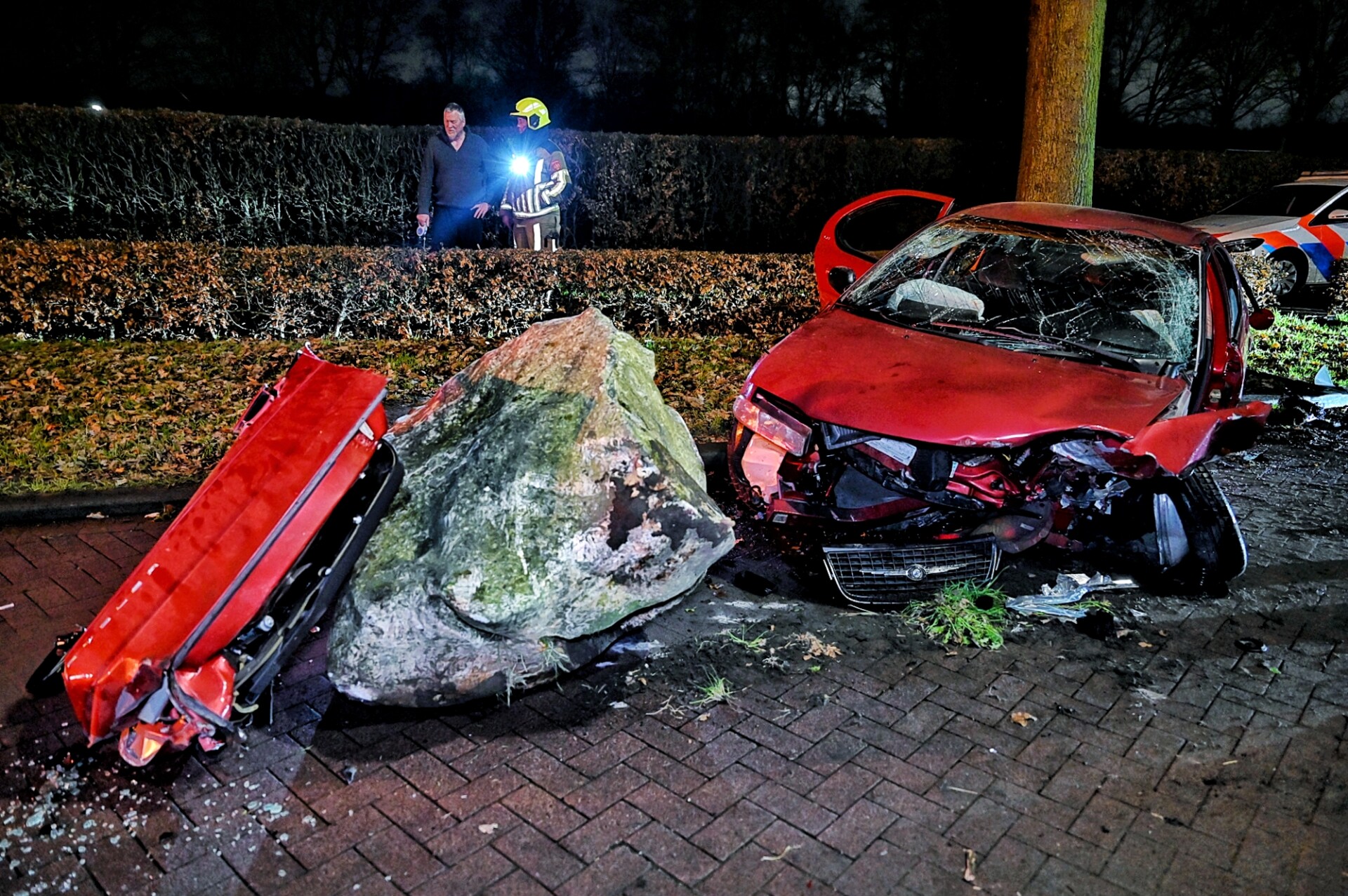 Auto botst tegen grote kei, bestuurder bekneld