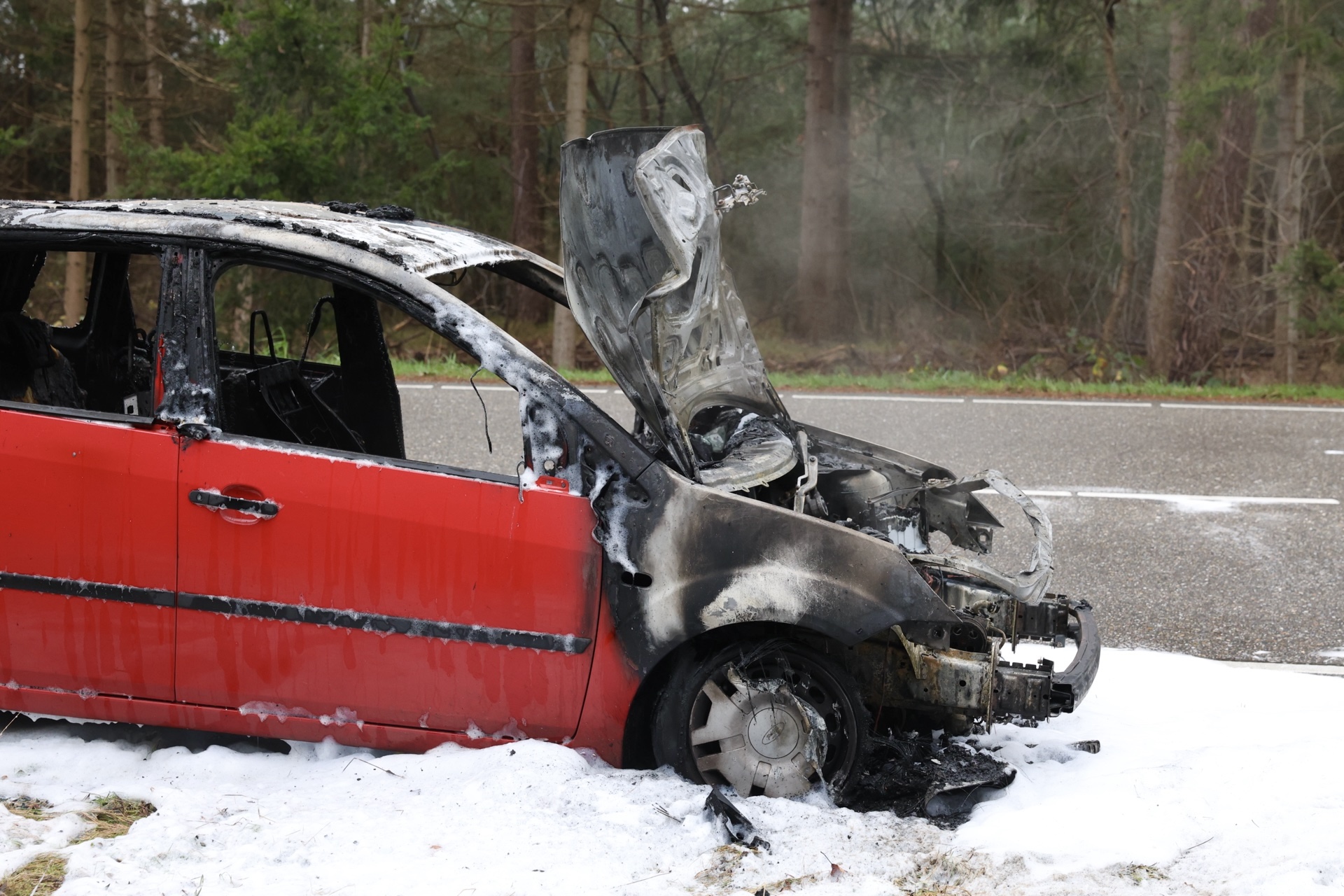 Autobrand geblust met schuim, weg deels dicht voor het verkeer