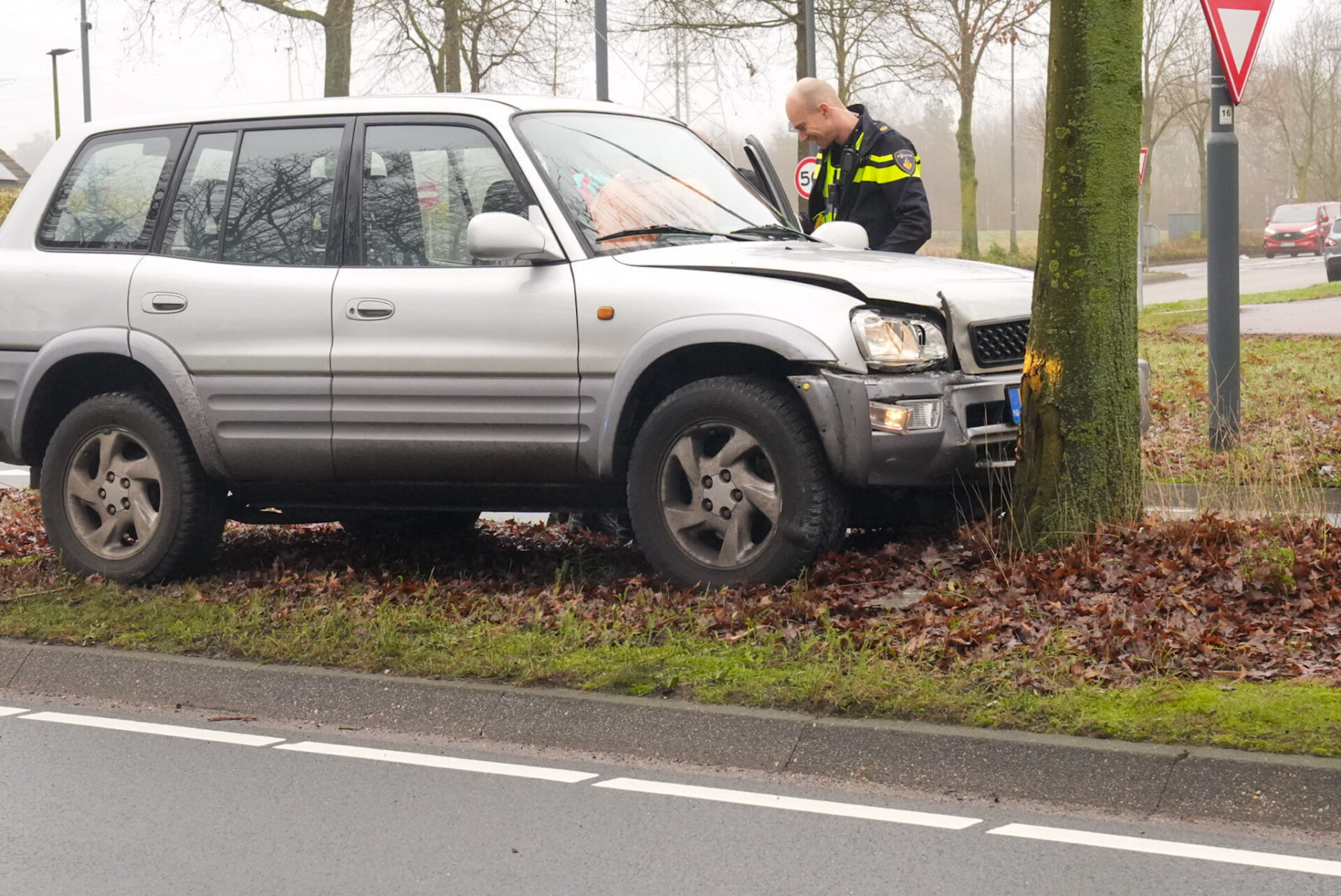 Man raakt bij verkeersplein van de weg en bots tegen boom
