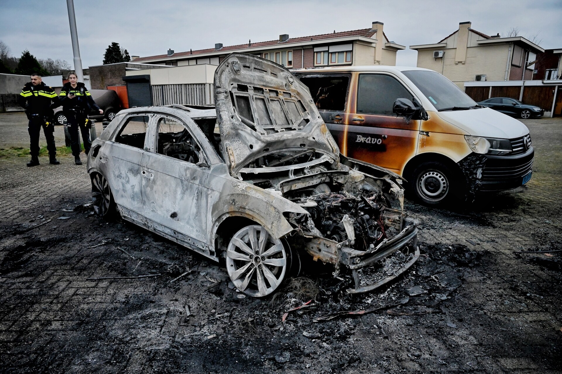 Auto en taxibus branden uit bij een binnenhof