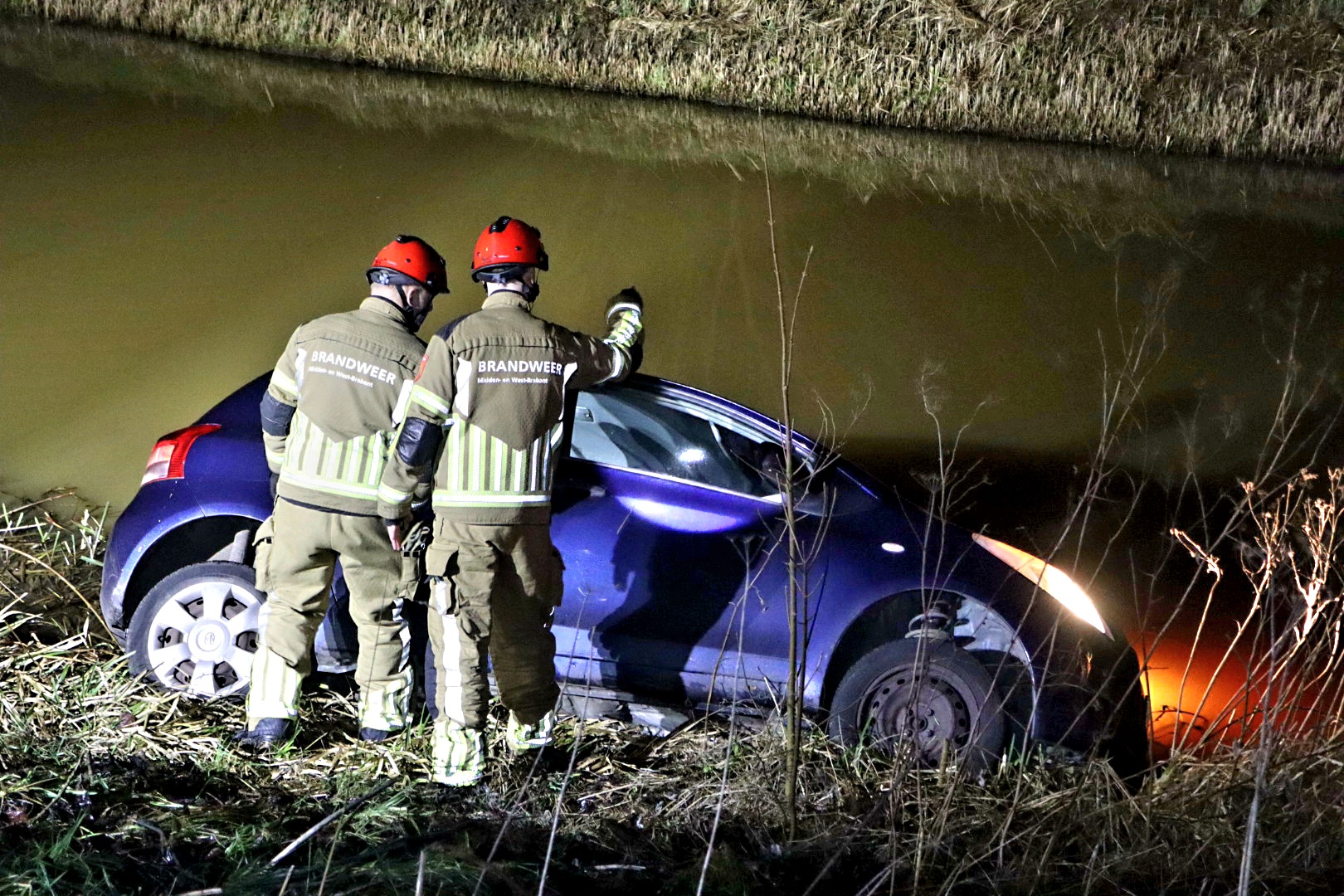 Auto belandt in sloot, automobiliste uit auto gered