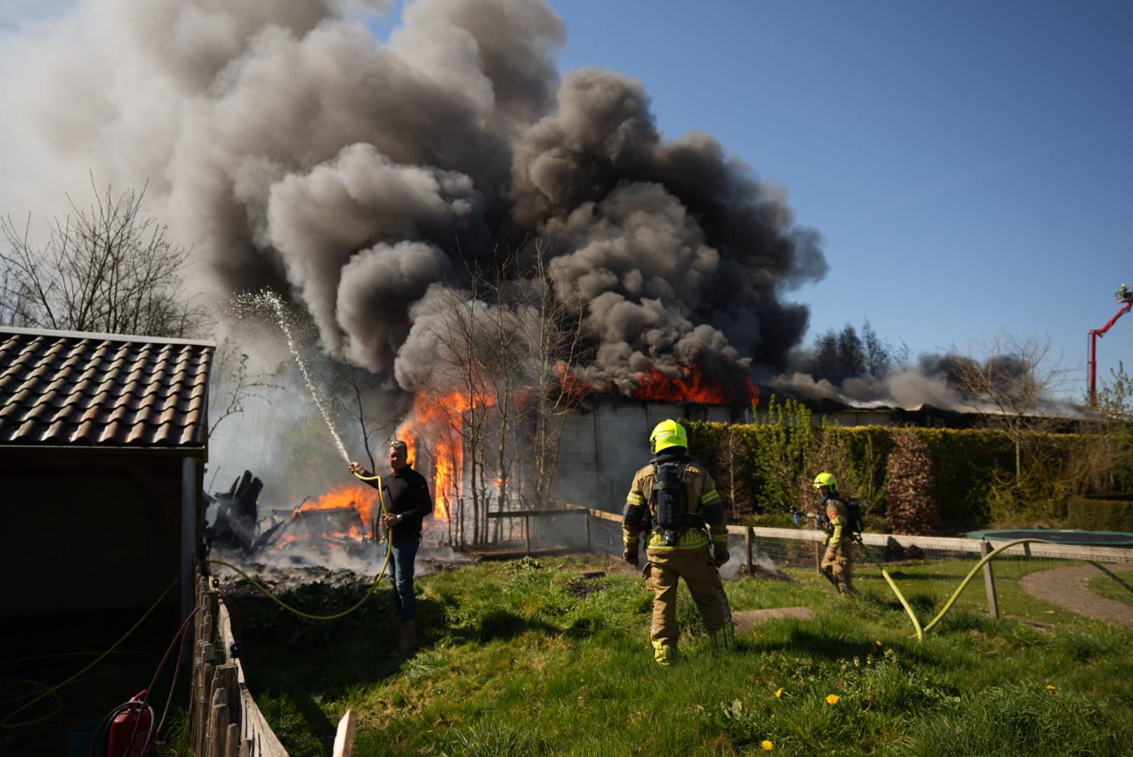 Zeer grote brand verwoest grote loods, rookwolken vanaf grote afstand zichtbaar