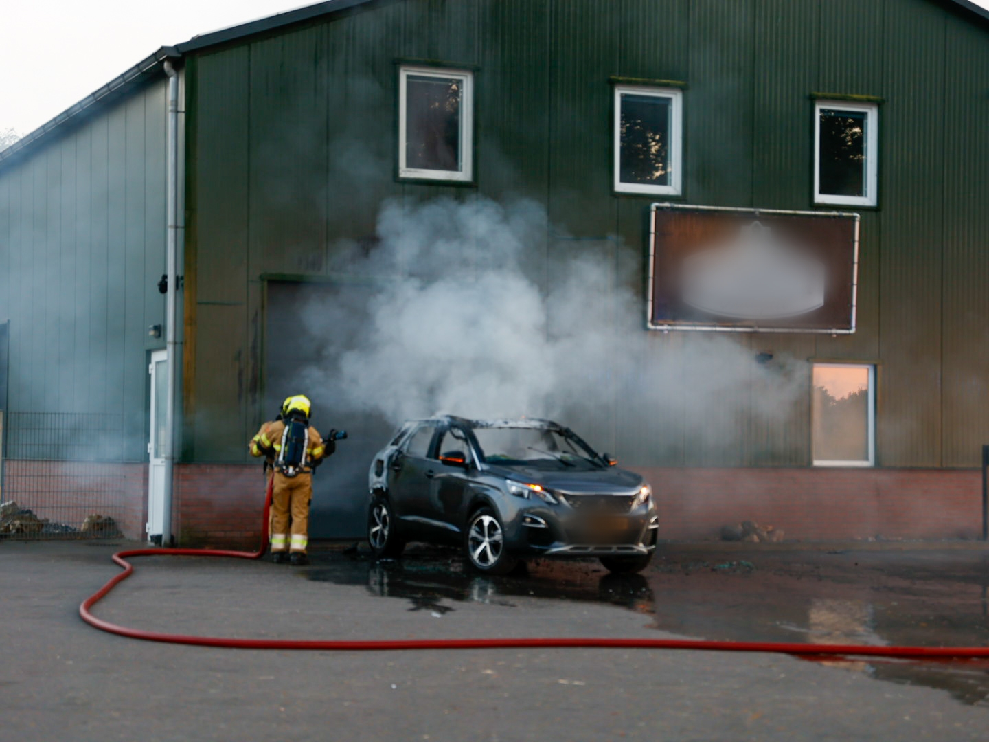 Auto vliegt in brand tegen bedrijfspand