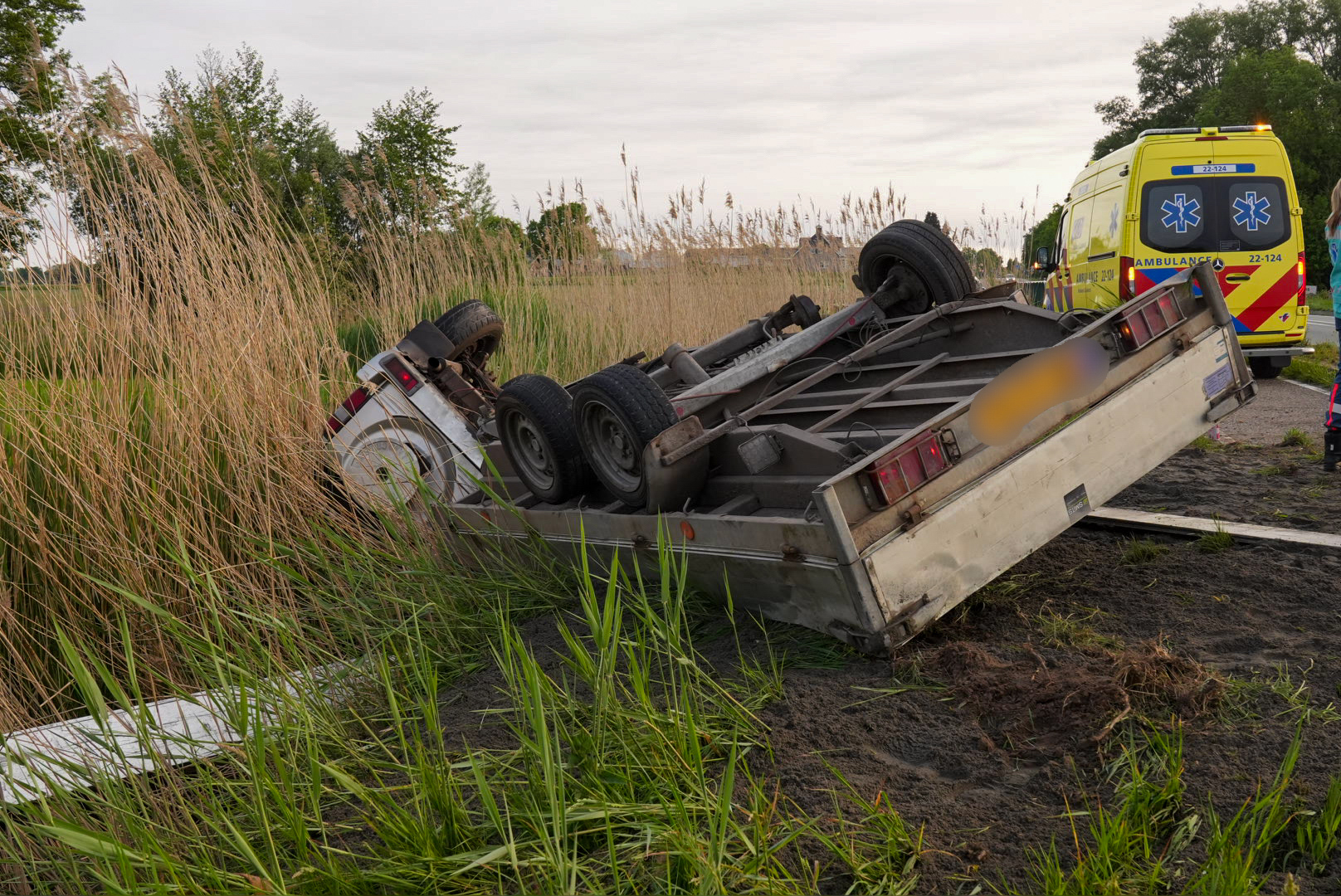 Auto met aanhanger belandt op zijn kant in de sloot
