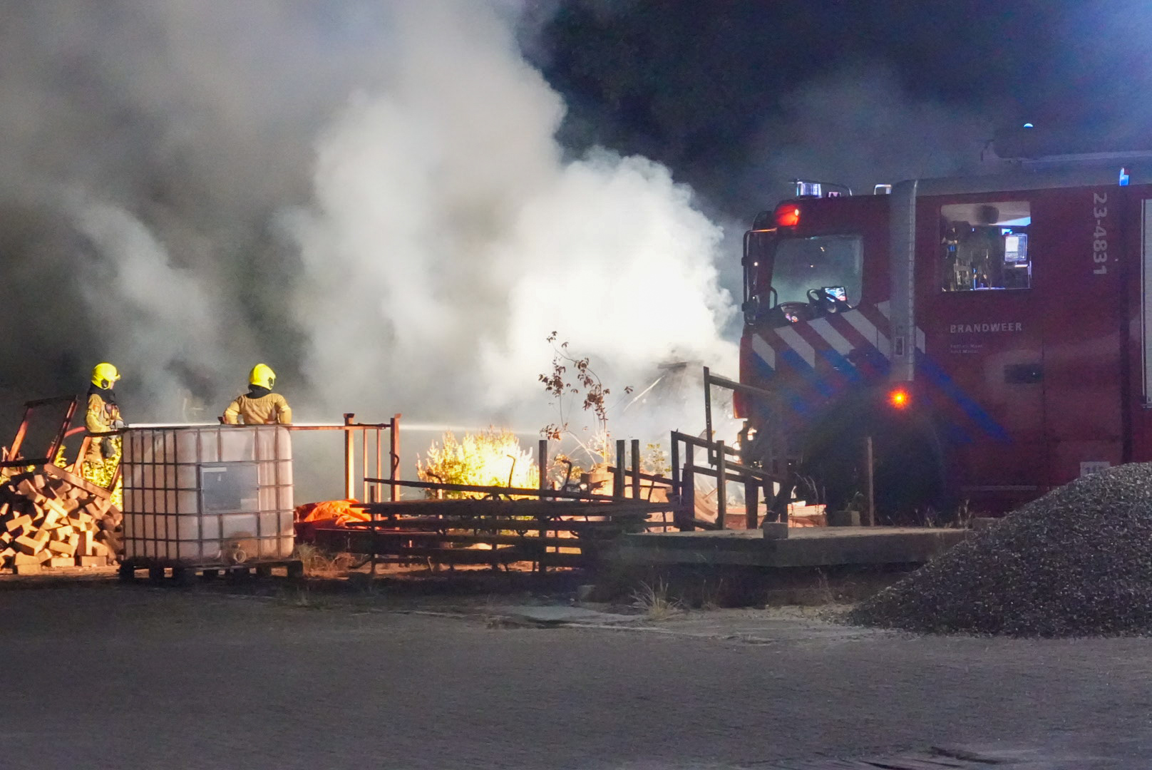 Grote berg met afval in brand agrarisch bedrijf
