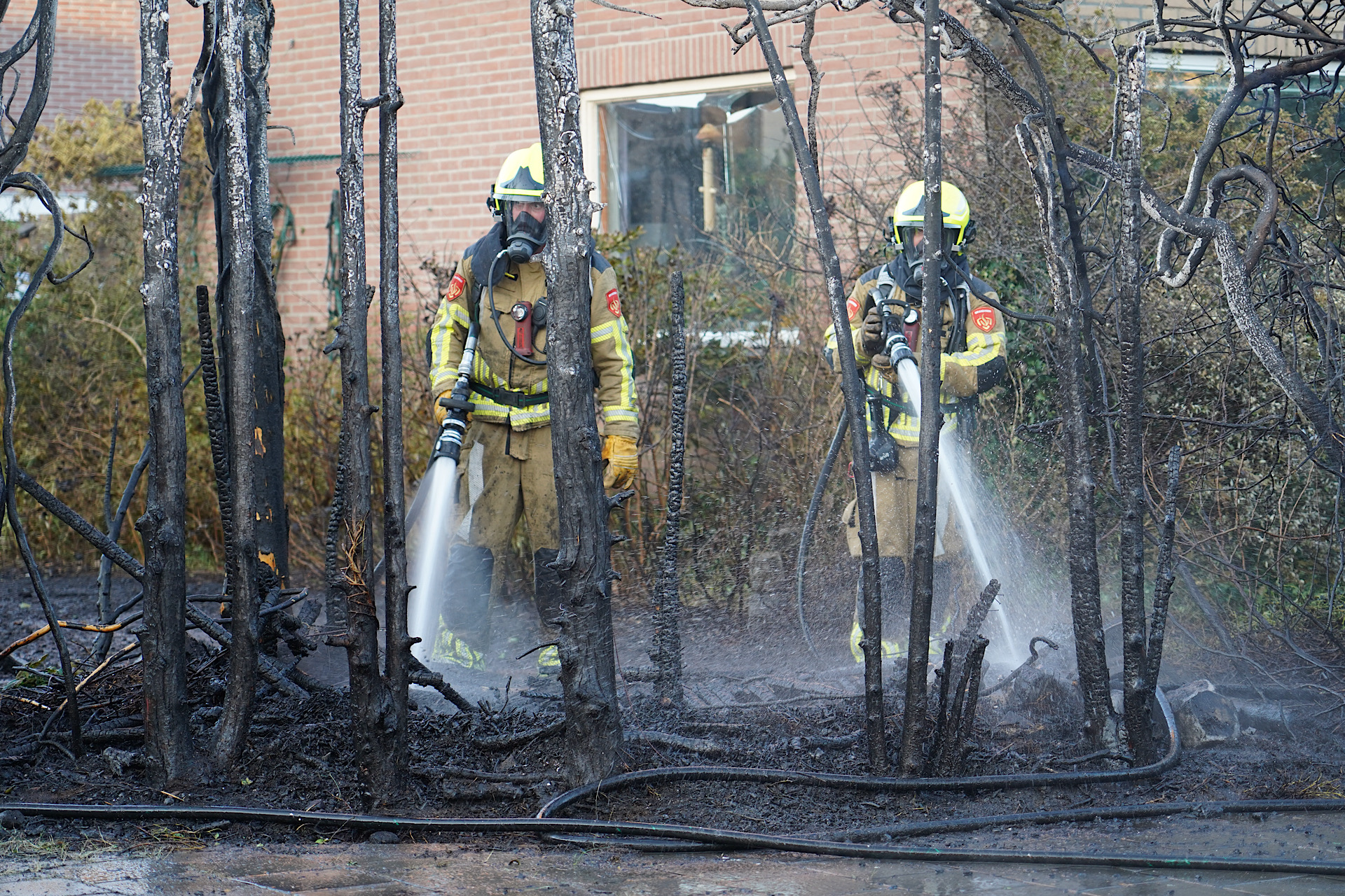 Felle brand verwoest heg en beschadigt auto; straat afgesloten
