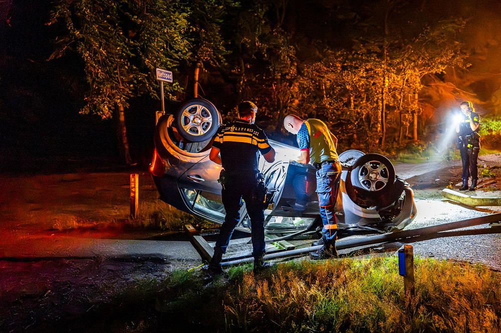 Auto over de kop na botsing tegen lantaarnpaal, bestuurder gewond