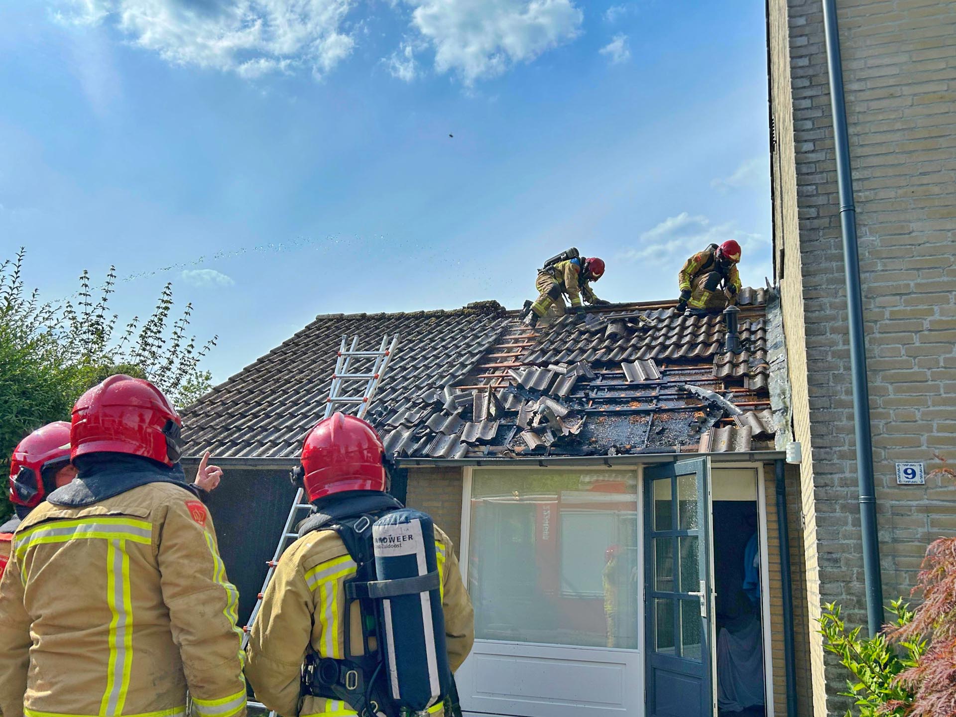 Overbuurman blust beginnende dakbrand met tuinslang