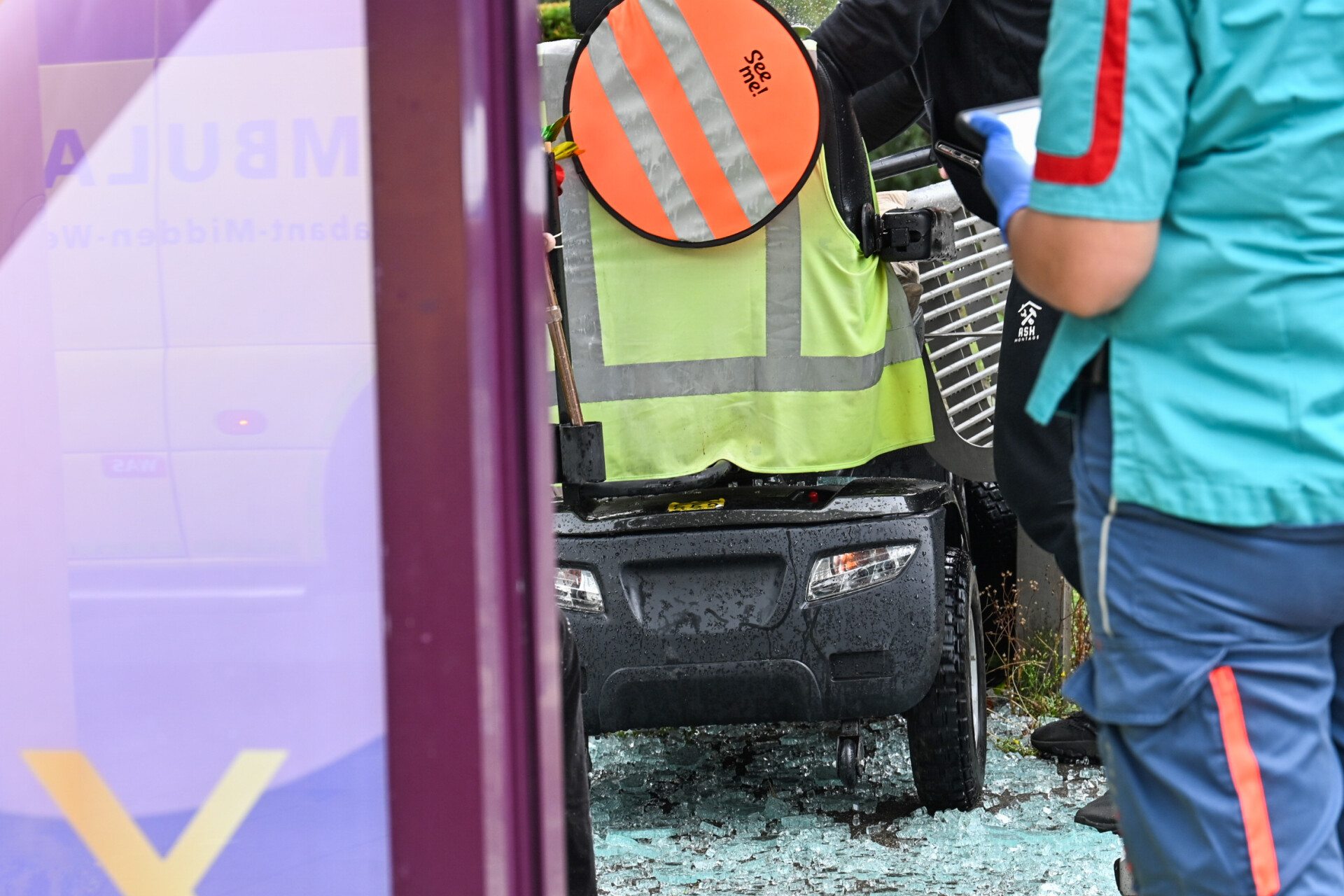 Oudere man rijdt met scootmobiel door bushokje