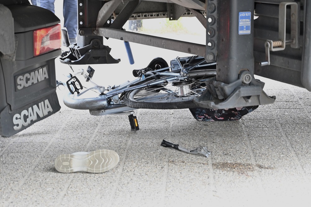 Vrouw komt met fiets onder vrachtwagen en raakt gewond