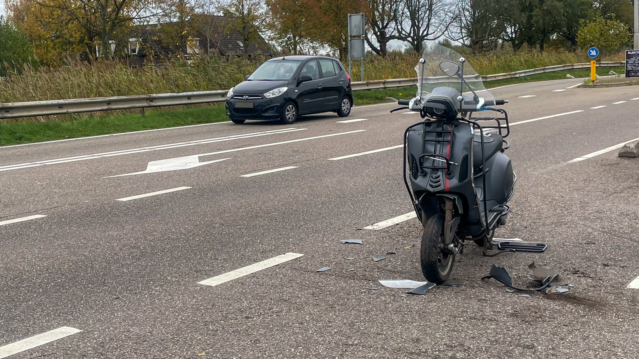Auto en scooter botsen bij inrit supermarkt