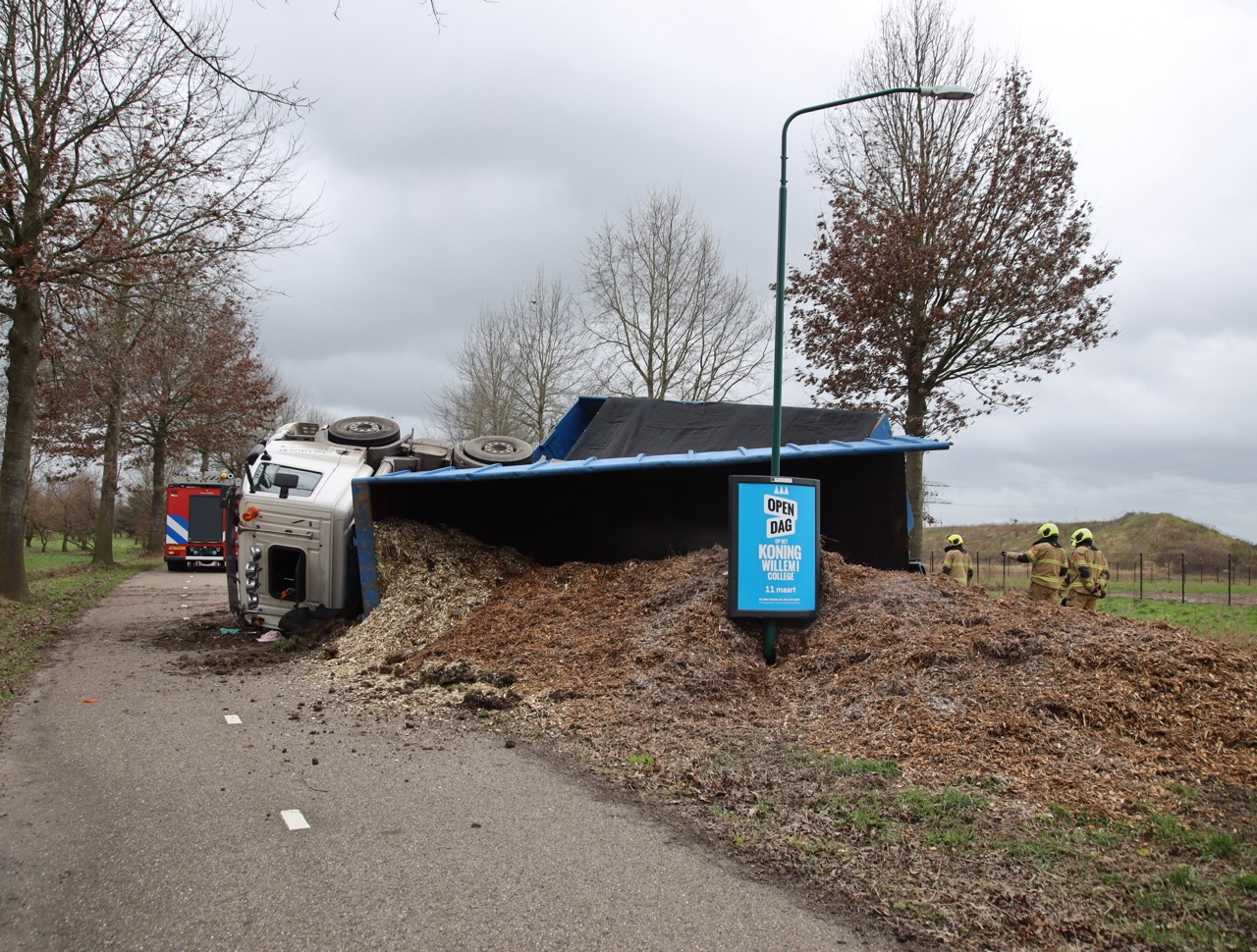 Vrachtwagen met houtsnippers gekanteld, weg volledig afgesloten