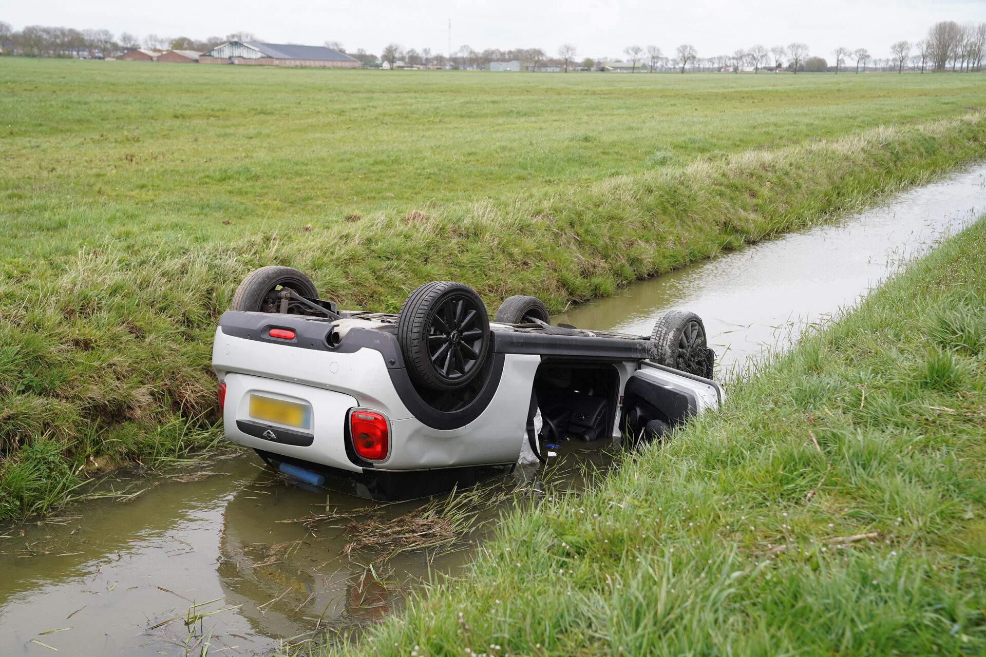 Auto belandt ondersteboven in sloot, inzittenden komen met nat pak weg