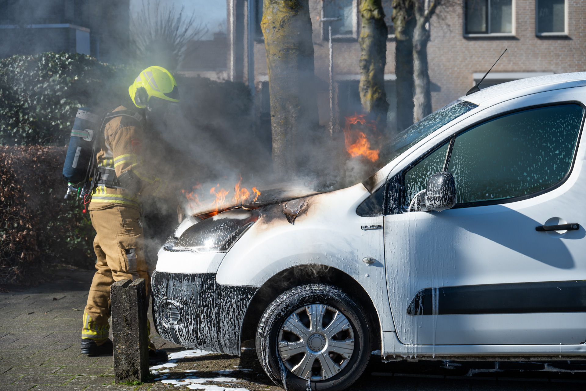 Auto vliegt in brand op parkeerplaats, omstander doet bluspoging met schuimblusser