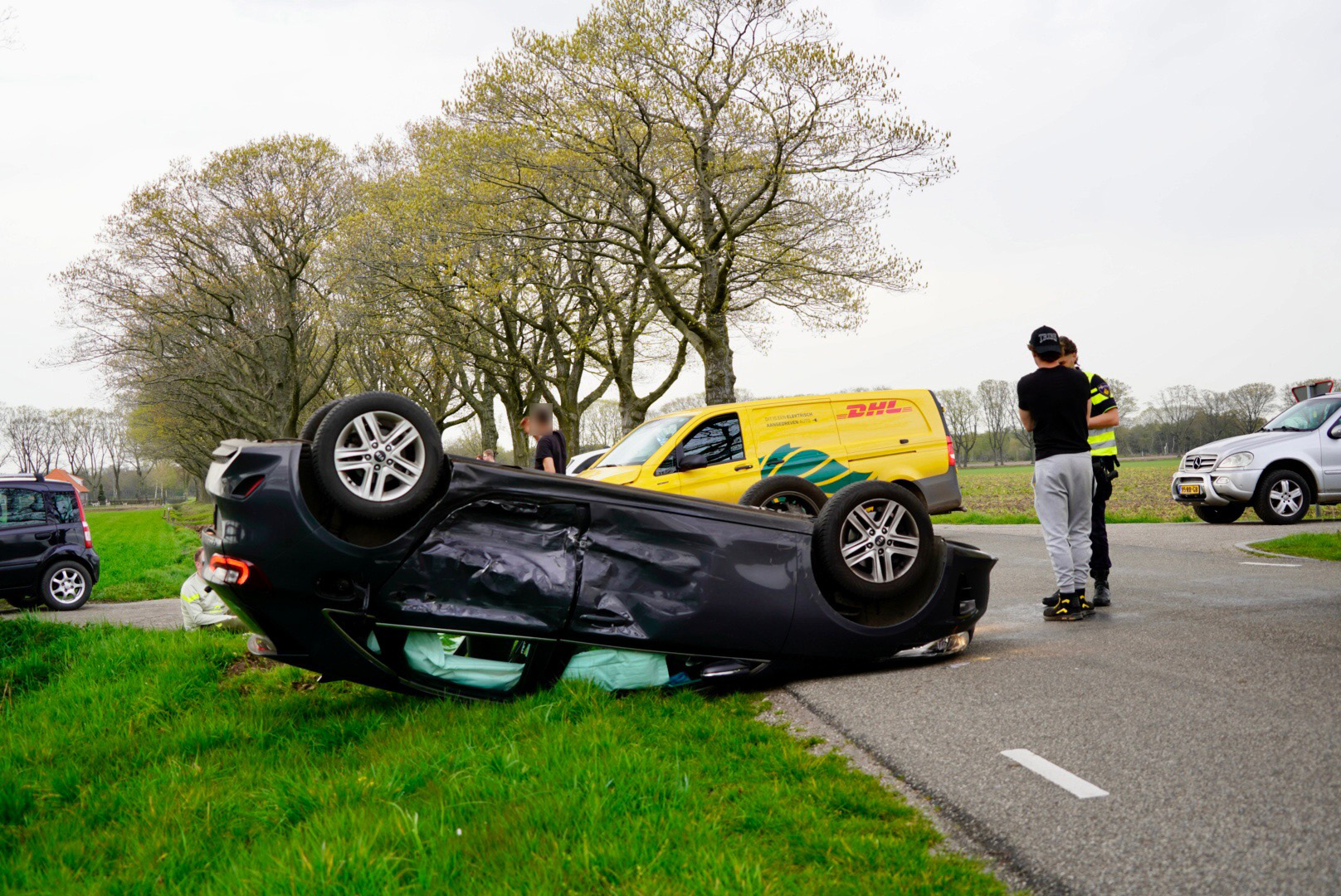 Auto op de kop na botsing met pakketbezorger