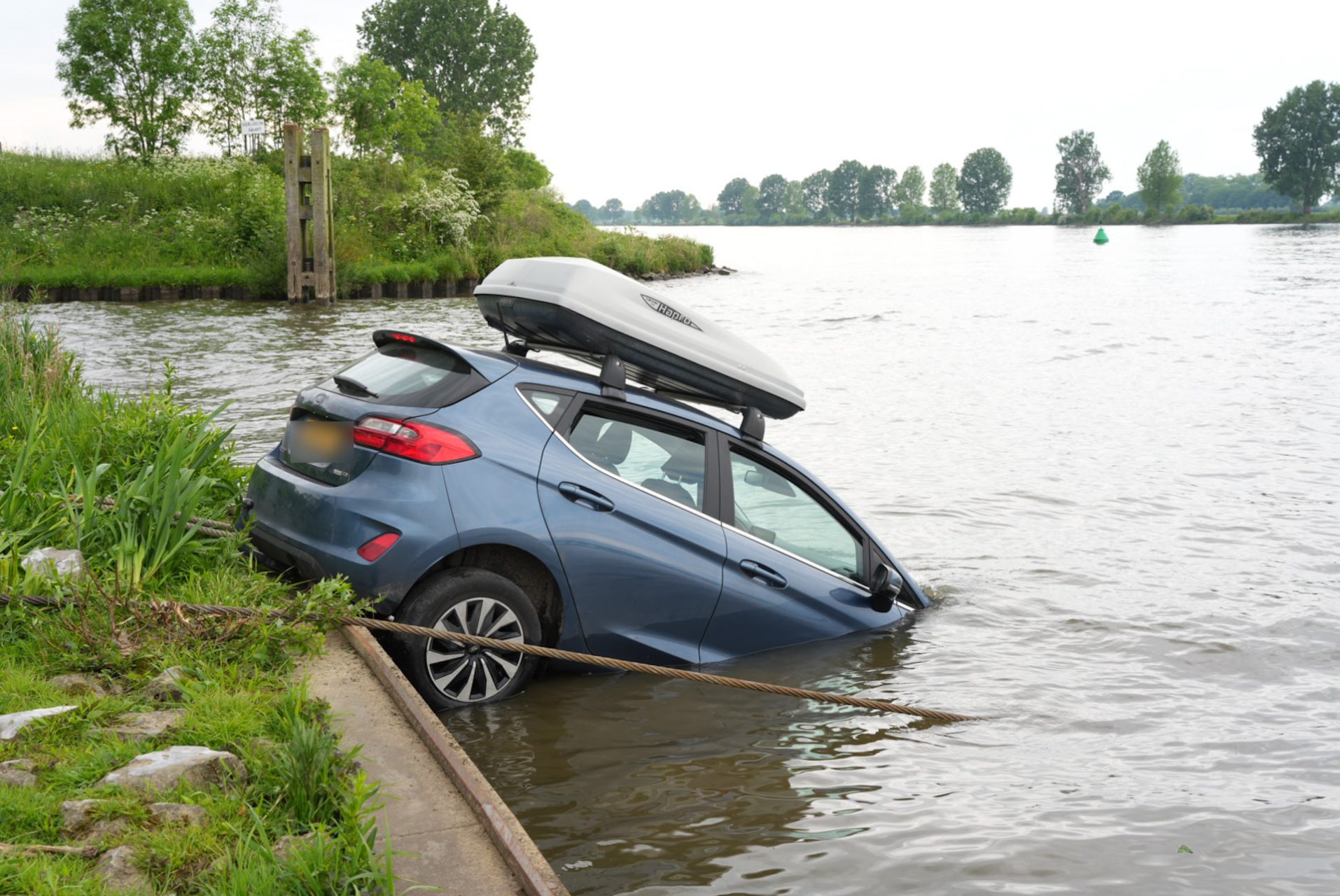 Auto rolt van veerstoep en belandt deels in water
