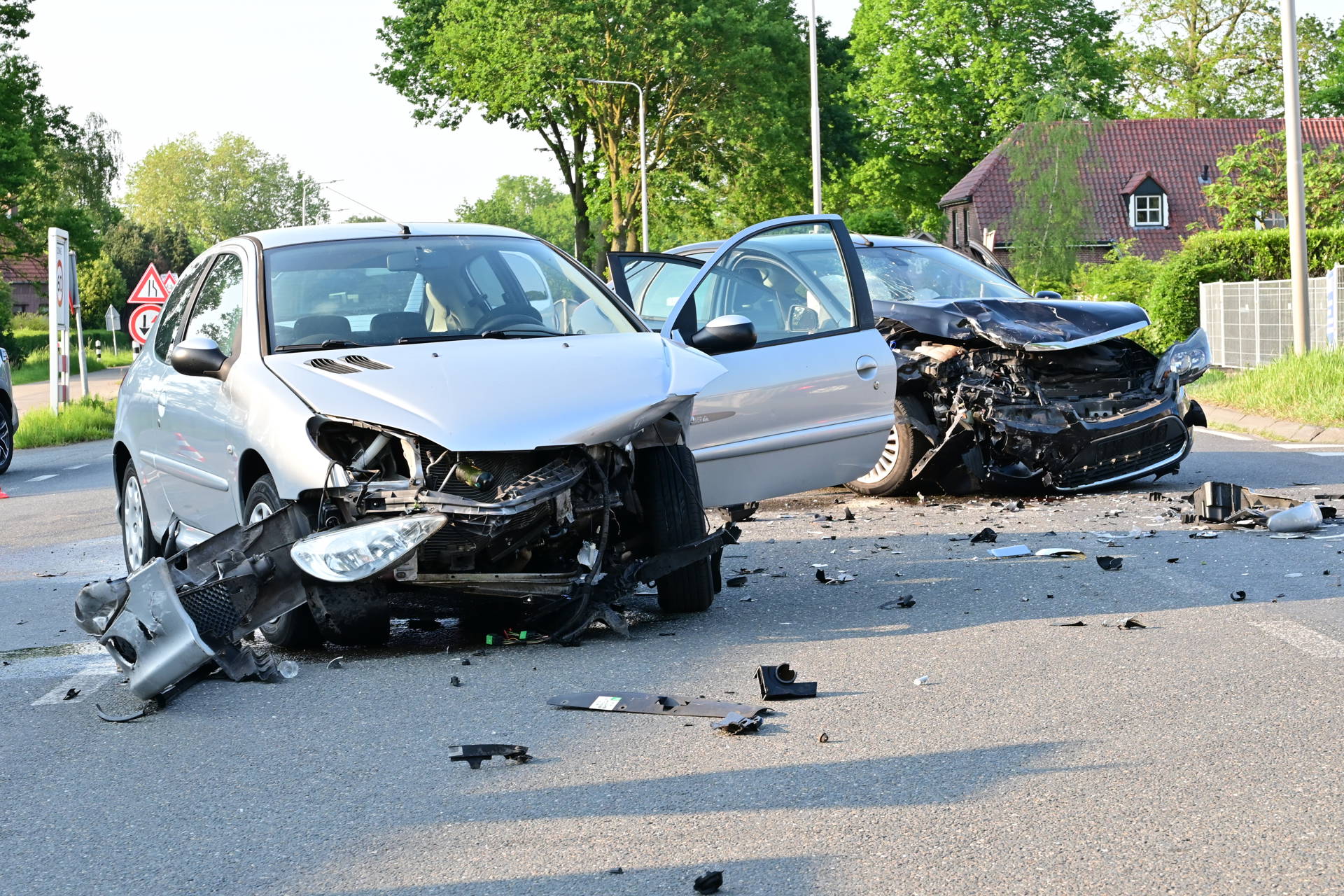 Twee auto’s botsen op kruispunt, weg bezaaid met brokstukken