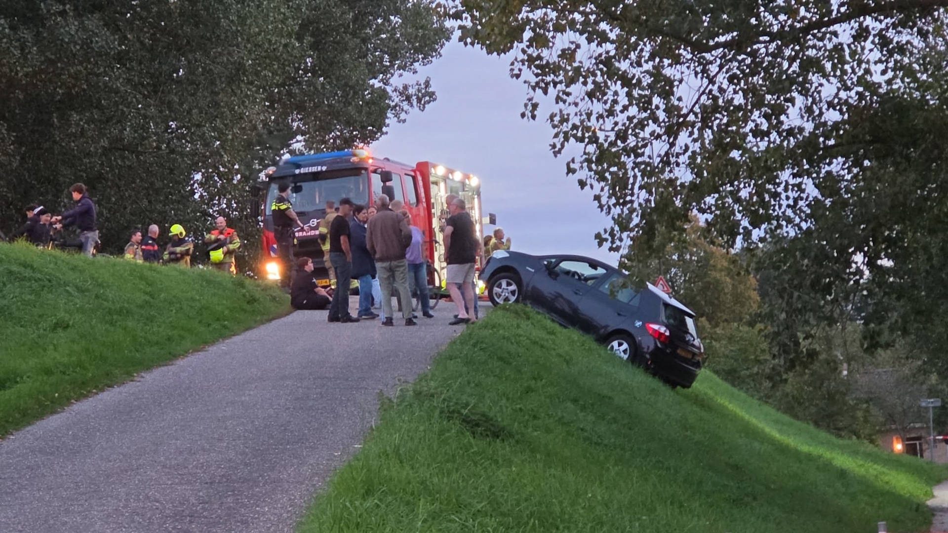 Auto raakt van dijk af en blijft gevaarlijk hangen